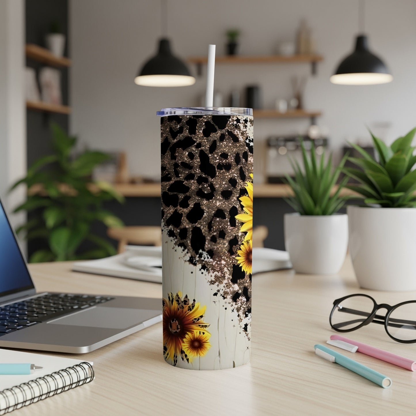 Sunflower and leopard print tumbler with straw on a desk.