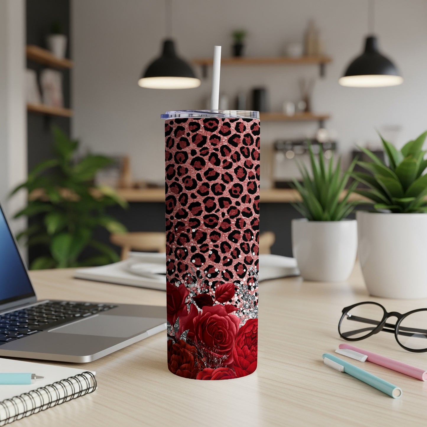 Red roses and leopard print tumbler with straw on desk.