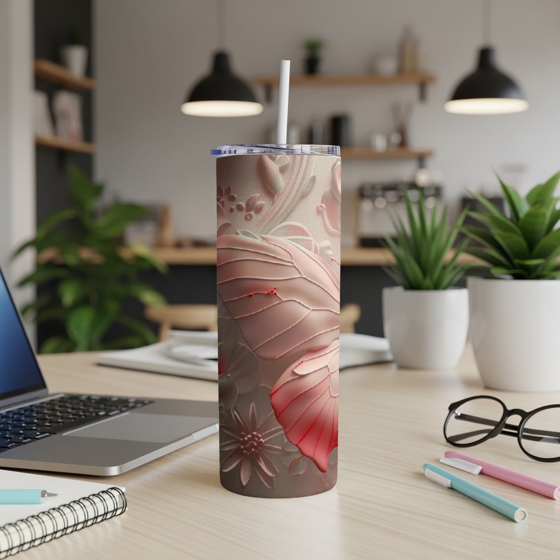 Pink floral embossed tumbler with straw on a desk.