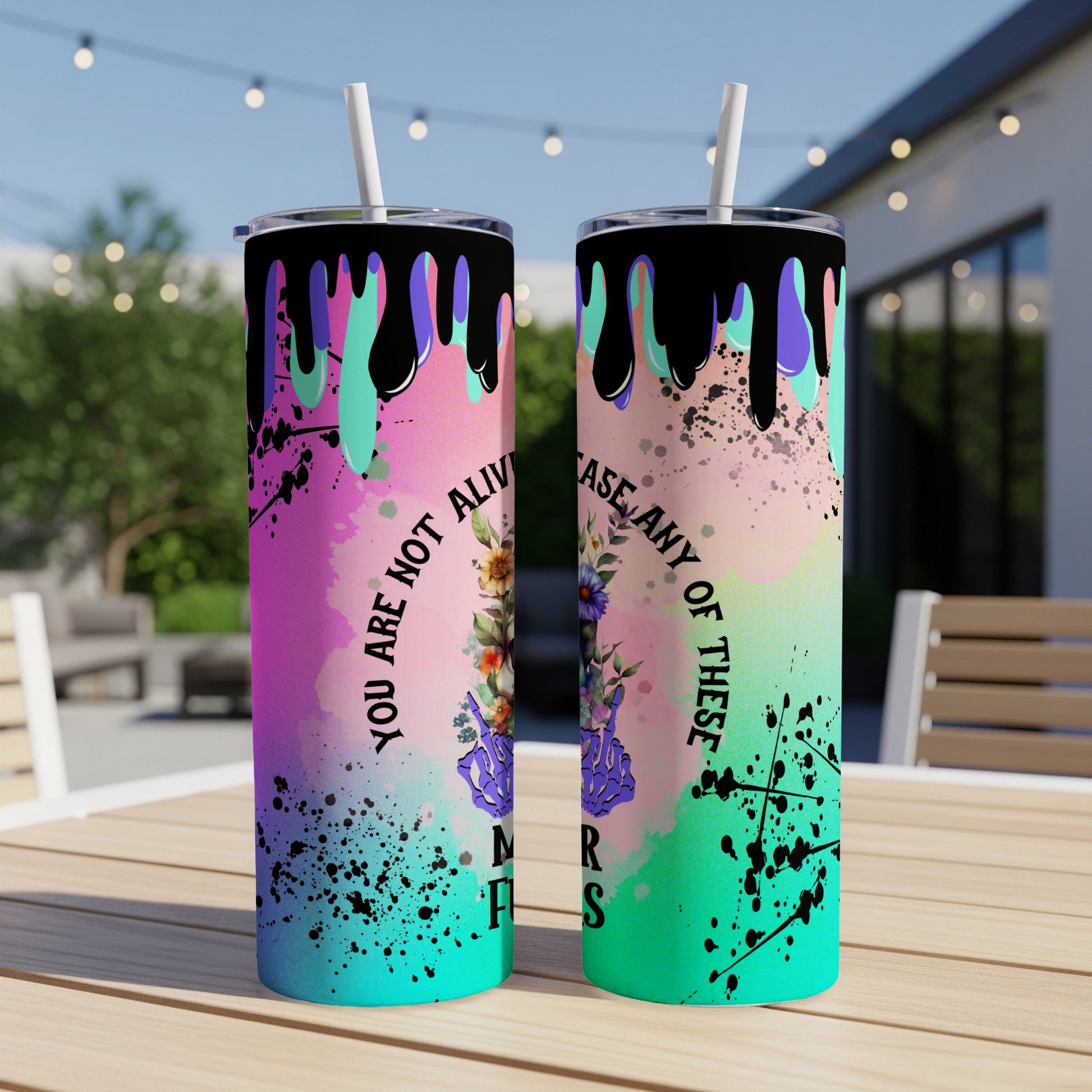 Pink and teal tumbler with abstract paint splatters and floral skull design.