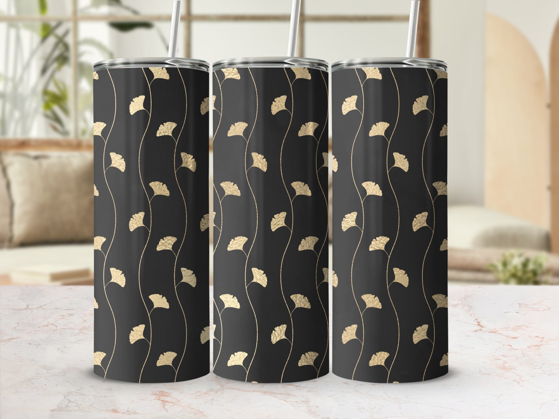 Three black tumblers with gold ginkgo leaf pattern and white straws.