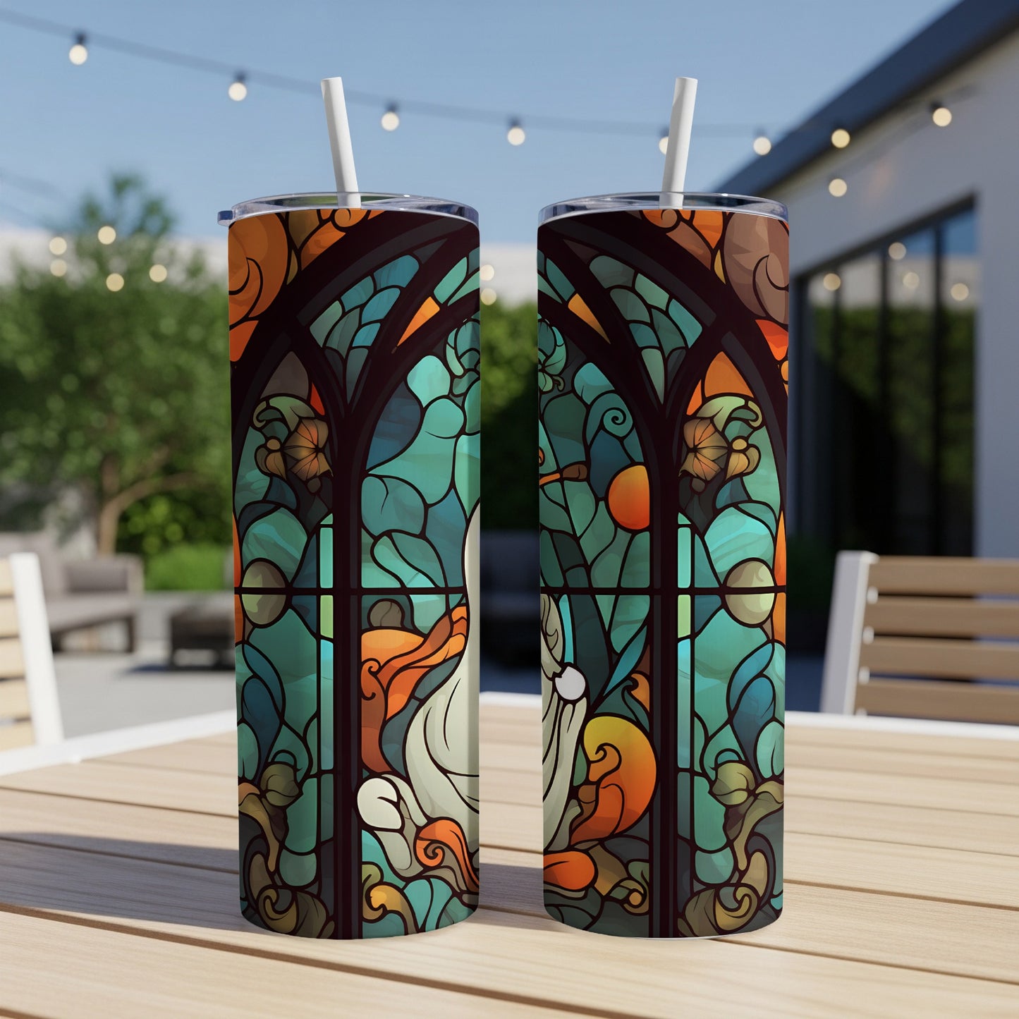 Two stained glass tumblers featuring abstract nature designs on a wooden table.