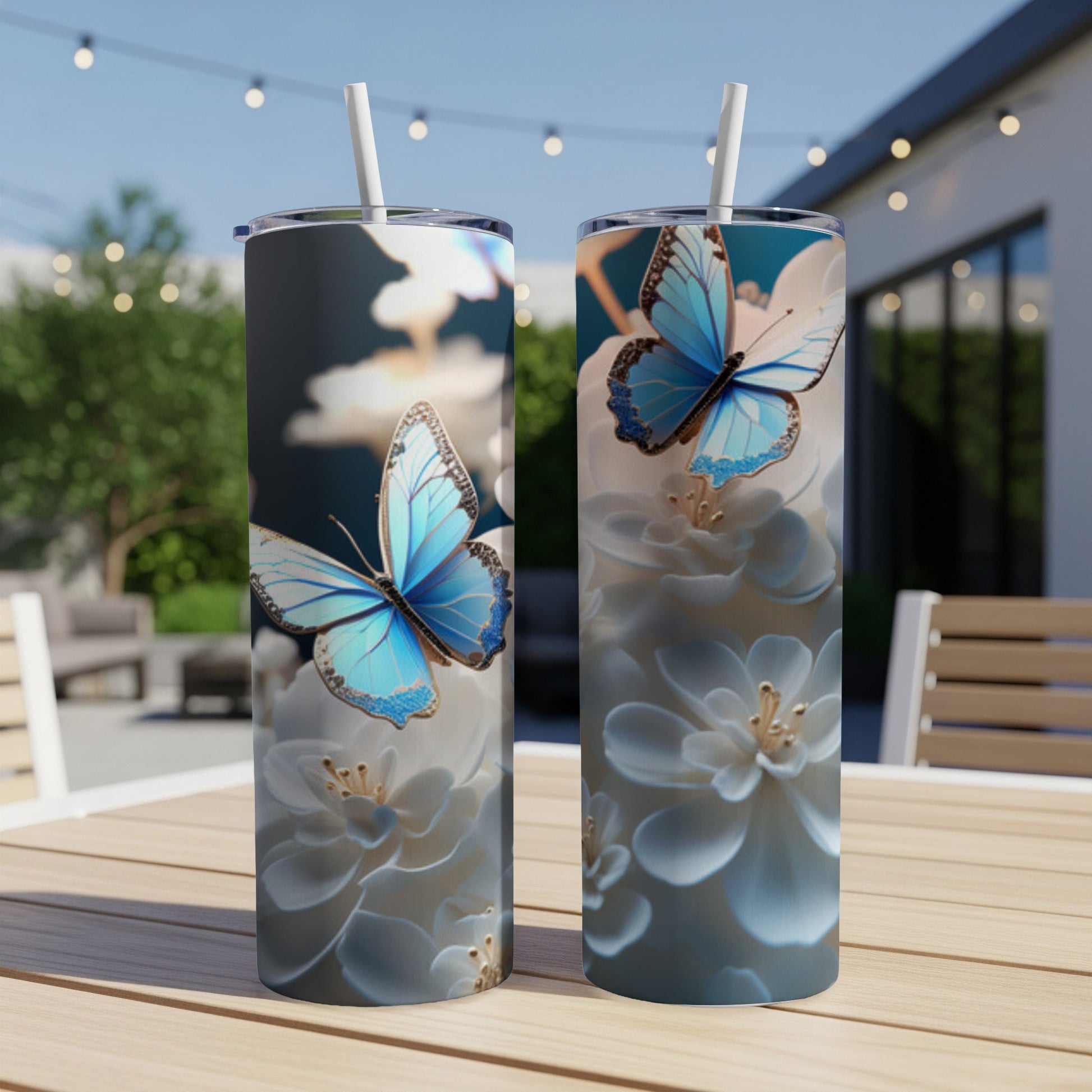 Two tall tumblers with blue butterflies and white flowers, outdoors.