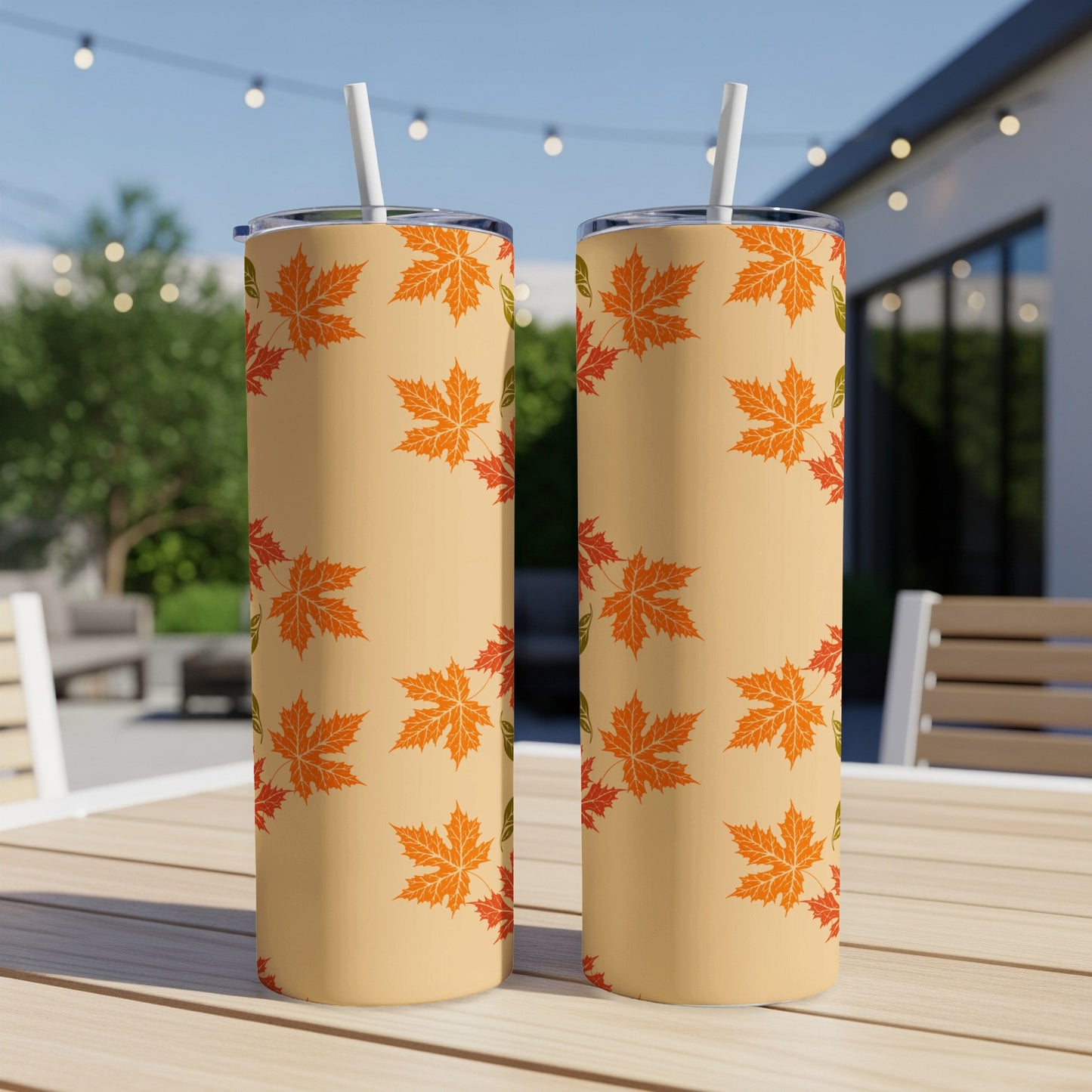 Two tan tumblers with orange and green maple leaf pattern.