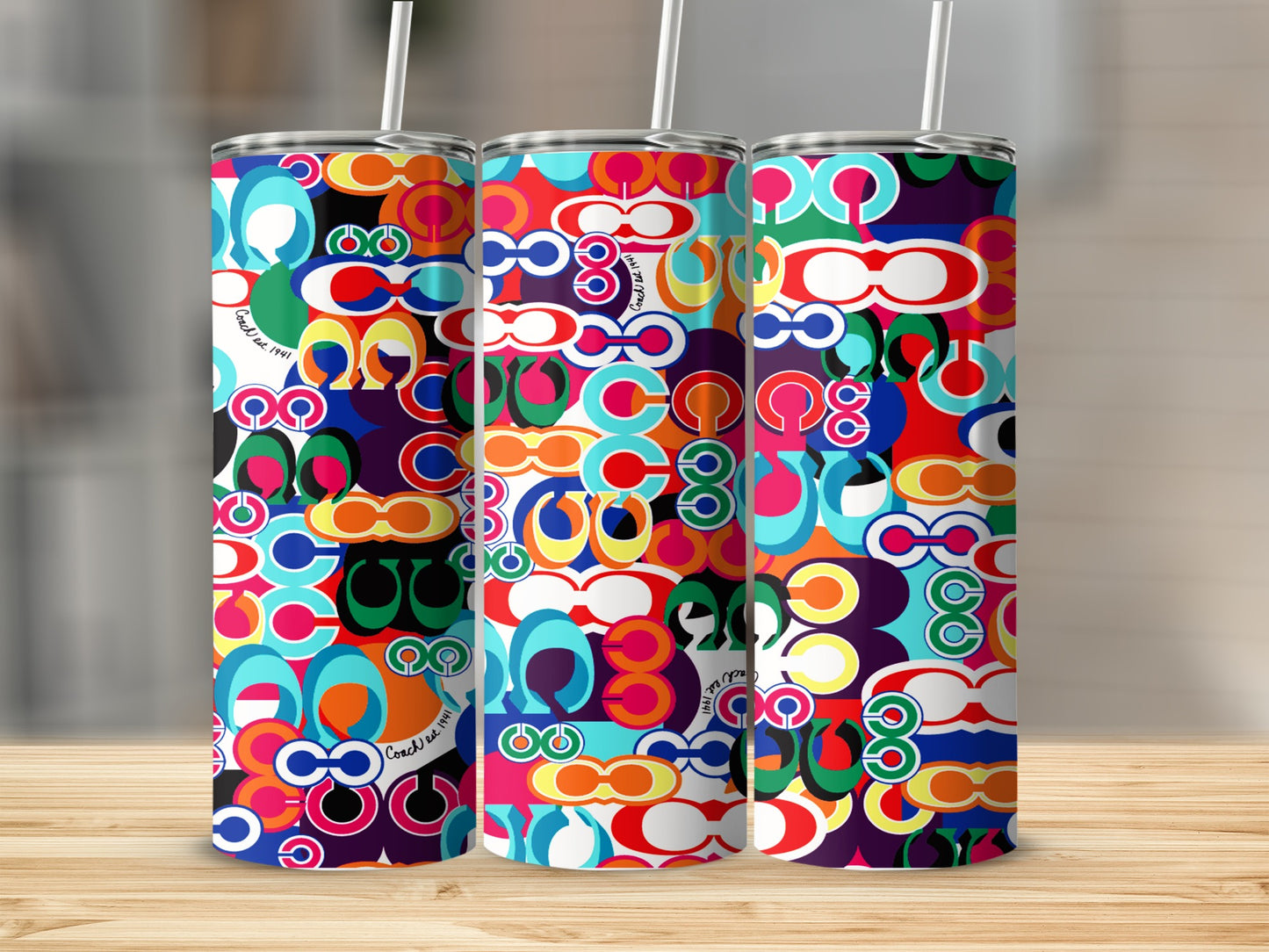 Three tumblers with a colorful geometric pattern of "C" shapes and "Coach est. 1941" text.