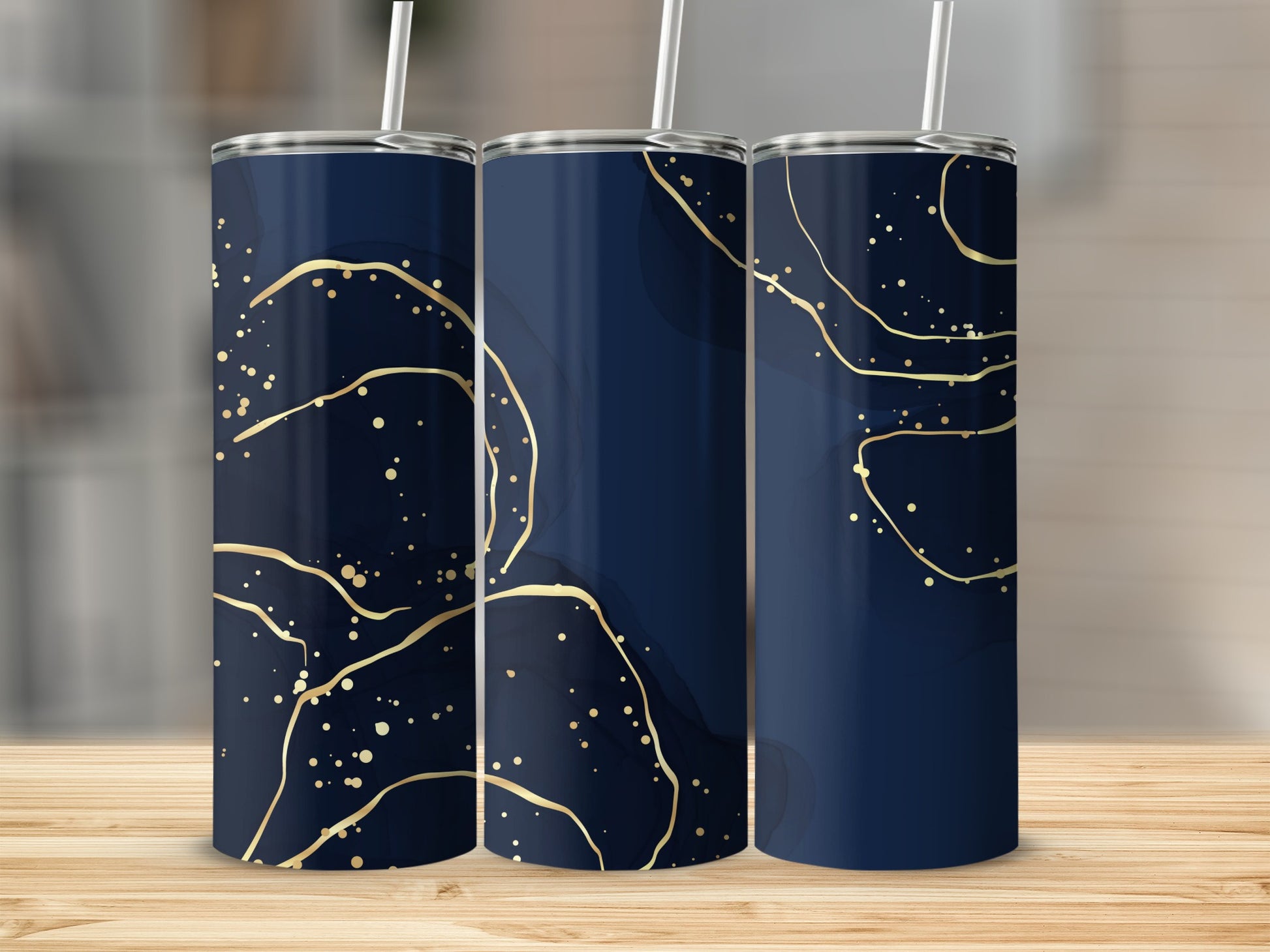 Three navy blue tumblers with abstract gold splatter and line designs.