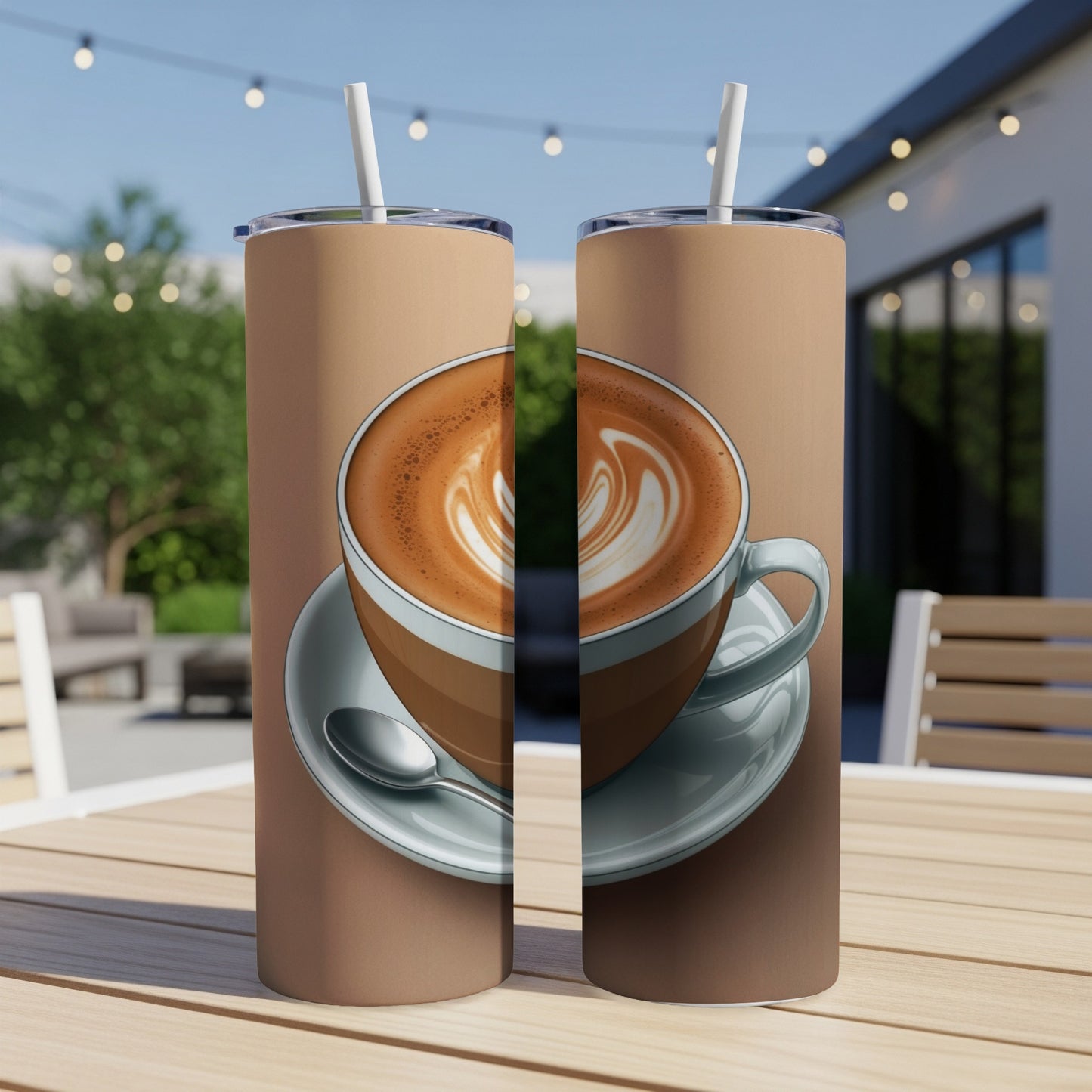 Two coffee tumblers with latte art, one spoon, and a straw on a table.