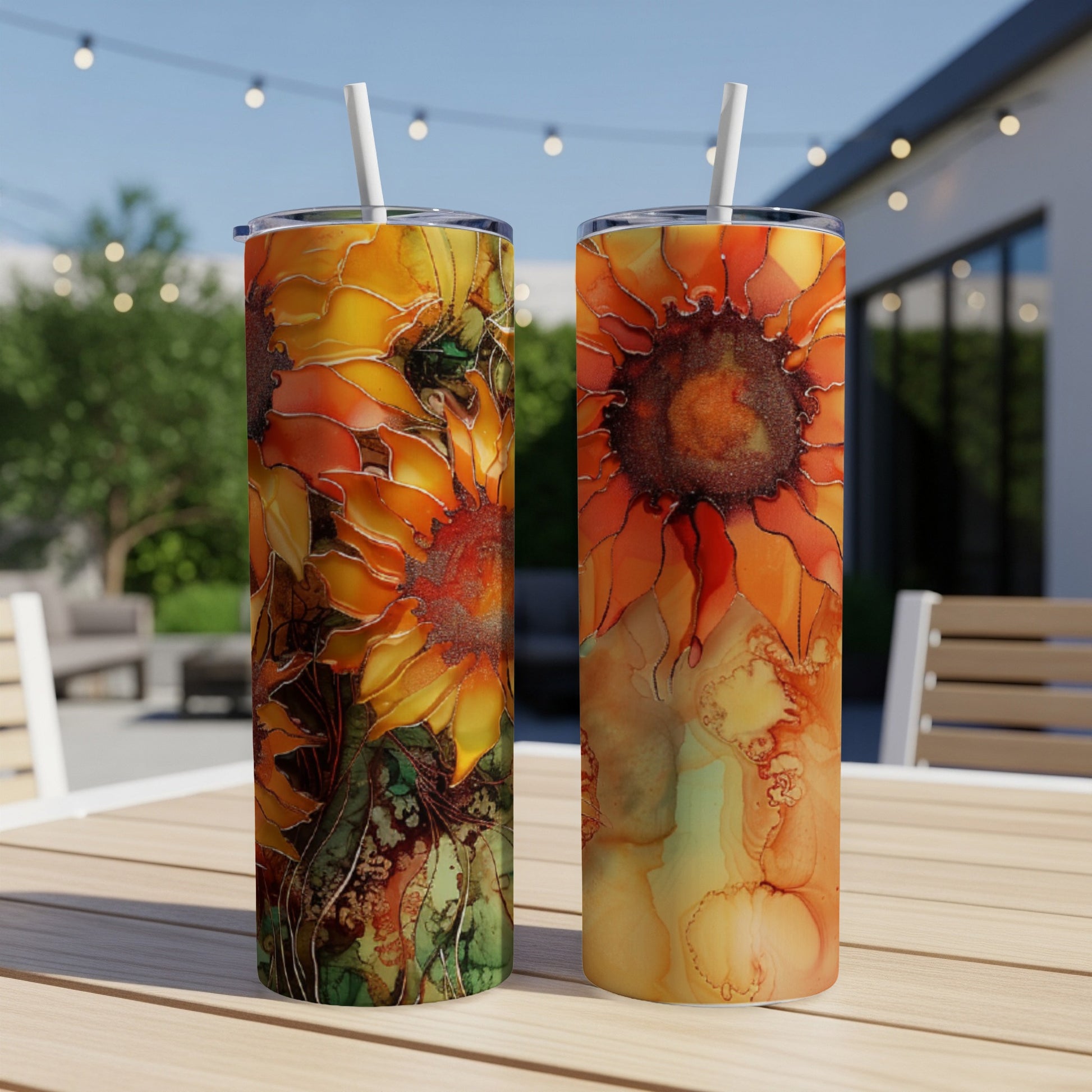 Two tumblers featuring vibrant, abstract sunflower art on a table outdoors.