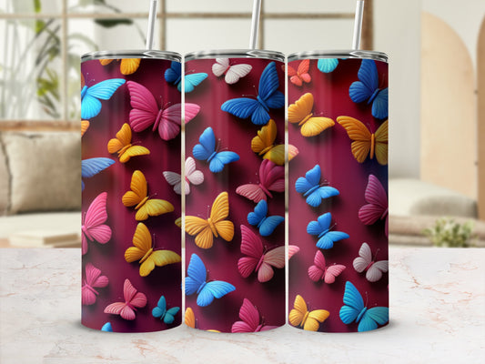 Three pink, blue, and yellow butterfly print tumblers with straws.