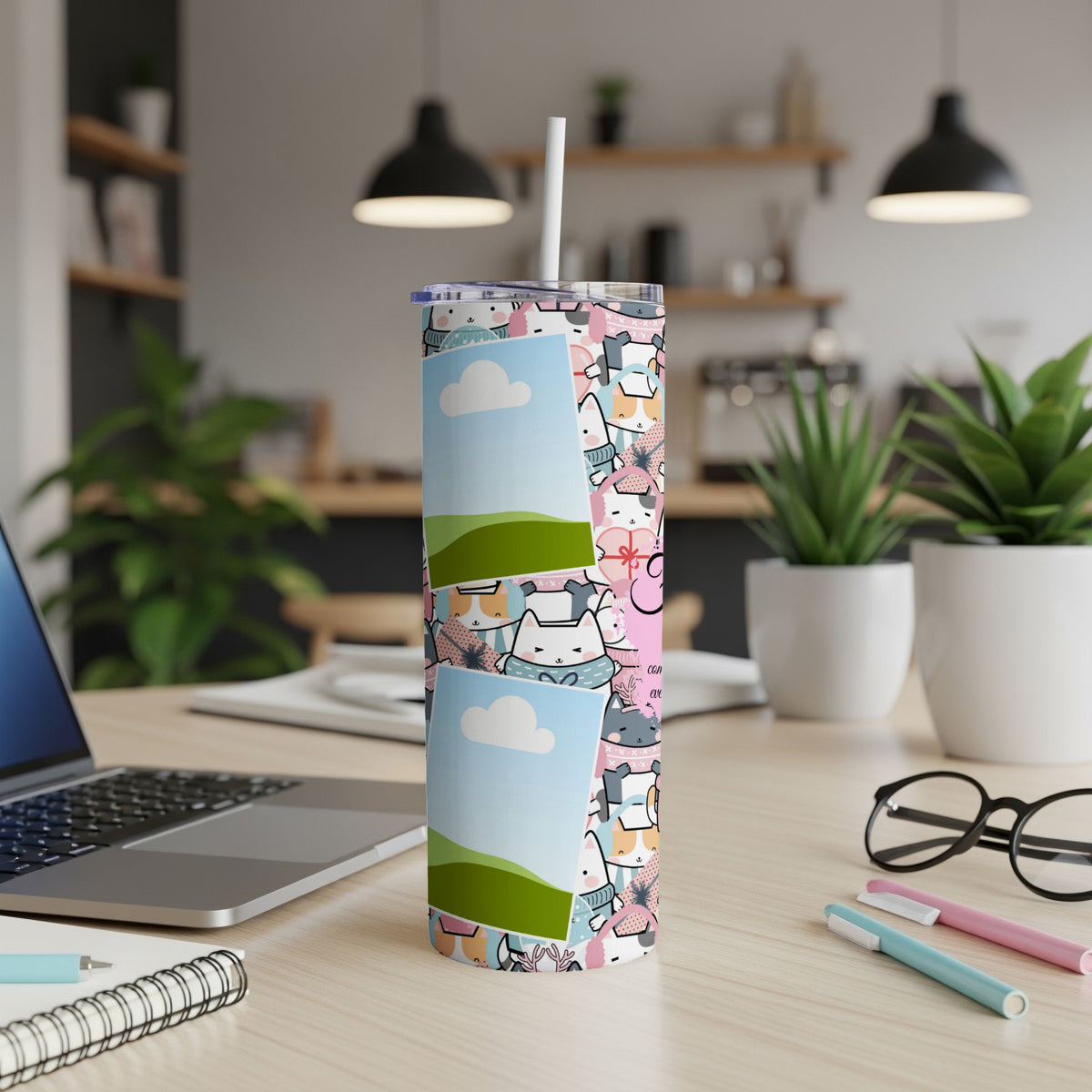 Tumbler with a cute cat pattern and blank picture frames, next to a laptop.