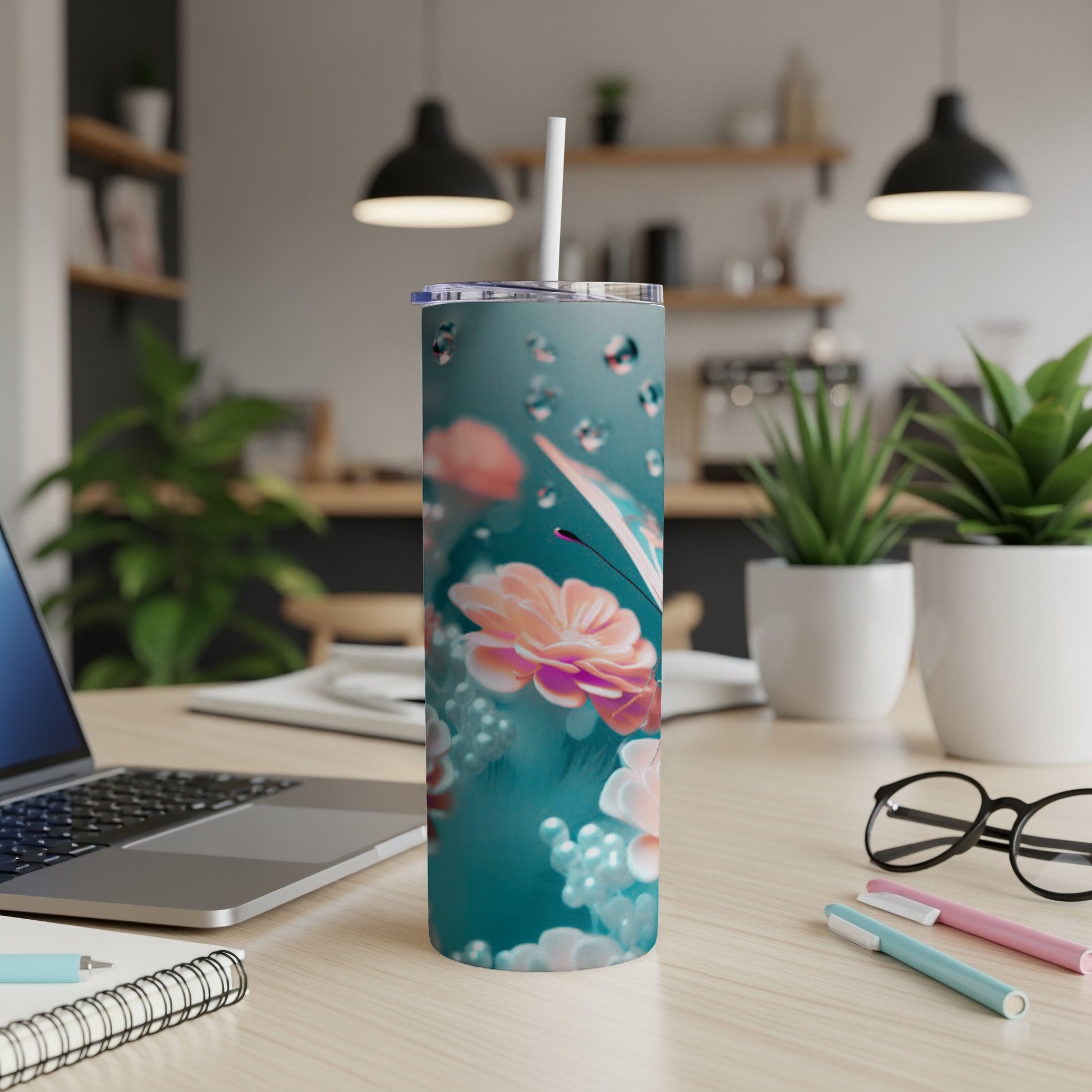 Teal tumbler with floral and bubble design, on a desk.