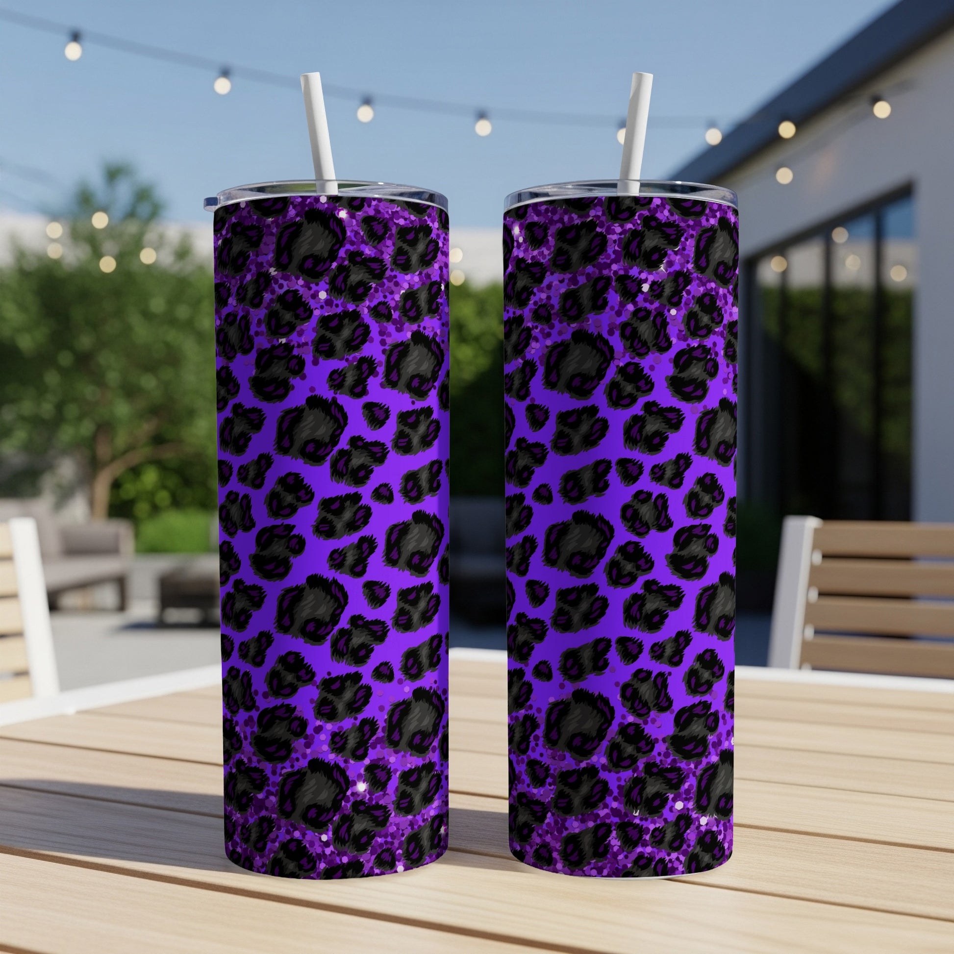 Two purple tumblers with black leopard print, on an outdoor table.