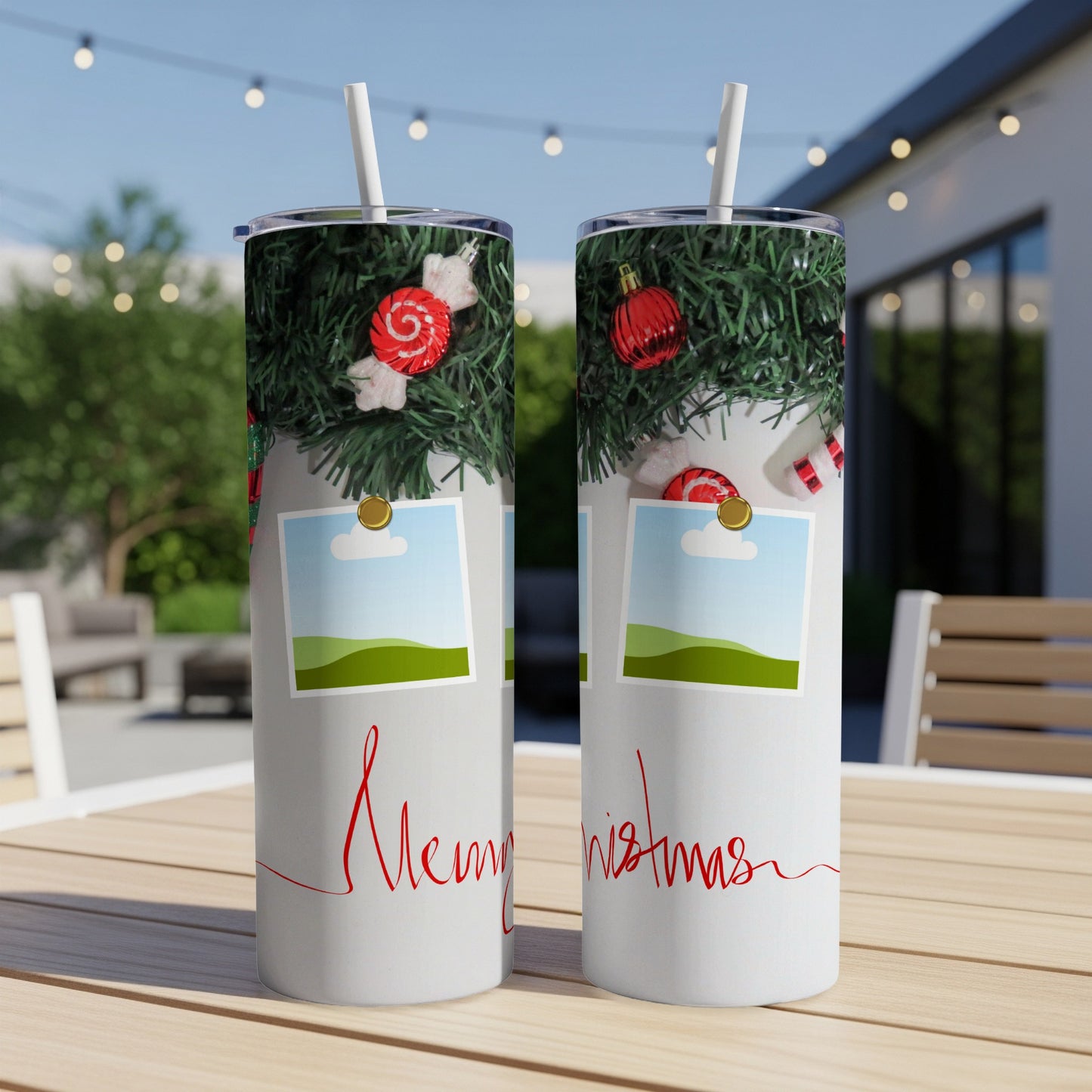 Two tumblers with Christmas garland and "Merry Christmas" text on an outdoor table.