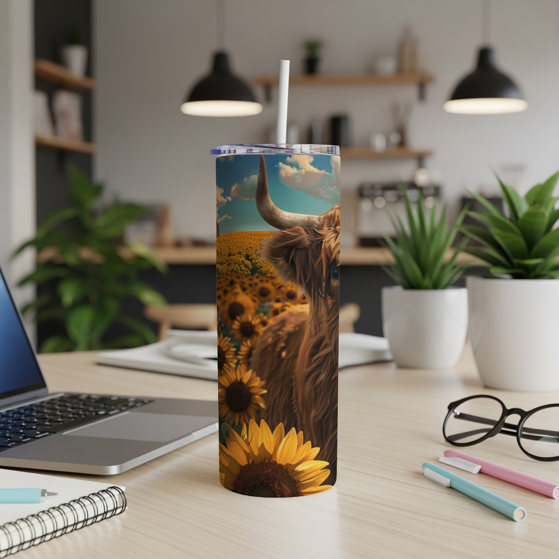 Highland cow in sunflower field on a tumbler with a laptop.
