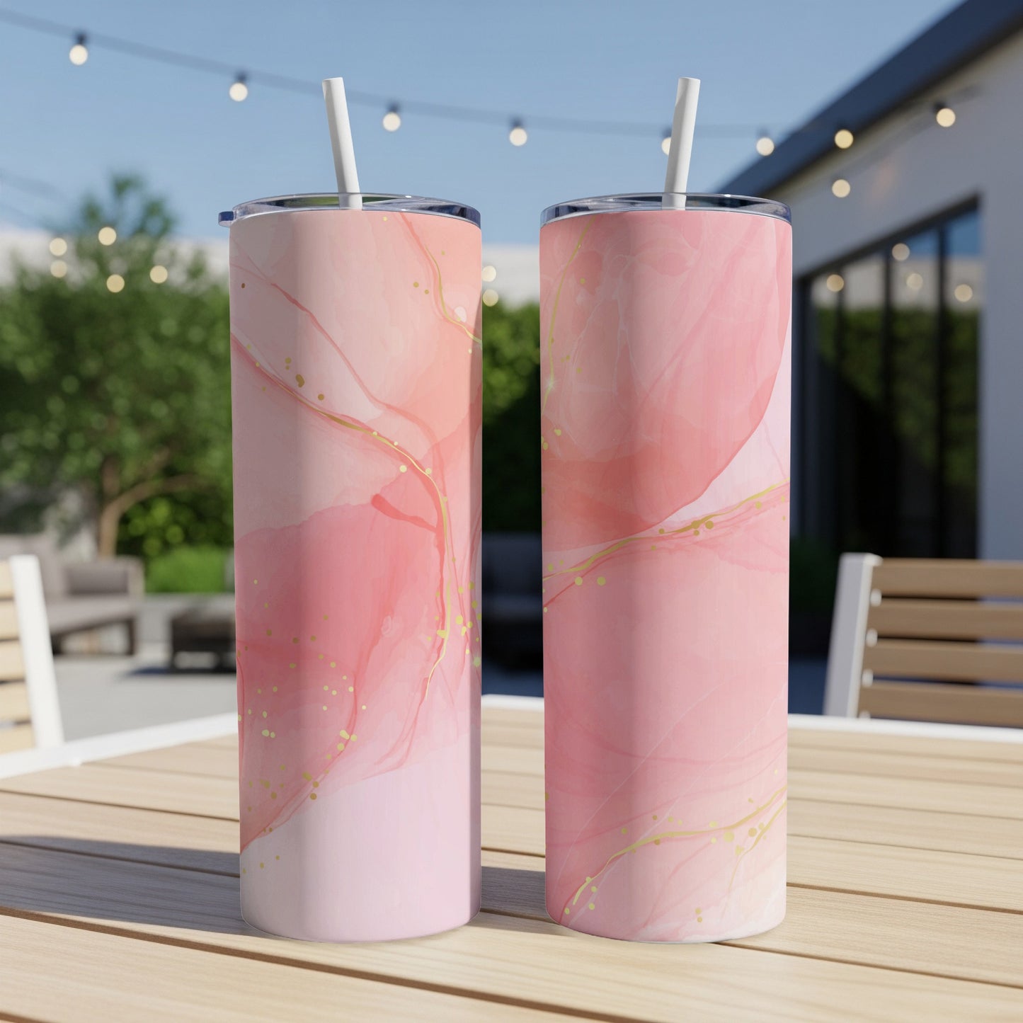 Two pink marble-patterned tumblers with gold flecks and straws.