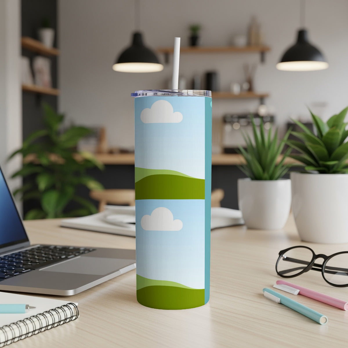 Tall tumbler with a cartoon sky and hills design and a white straw.