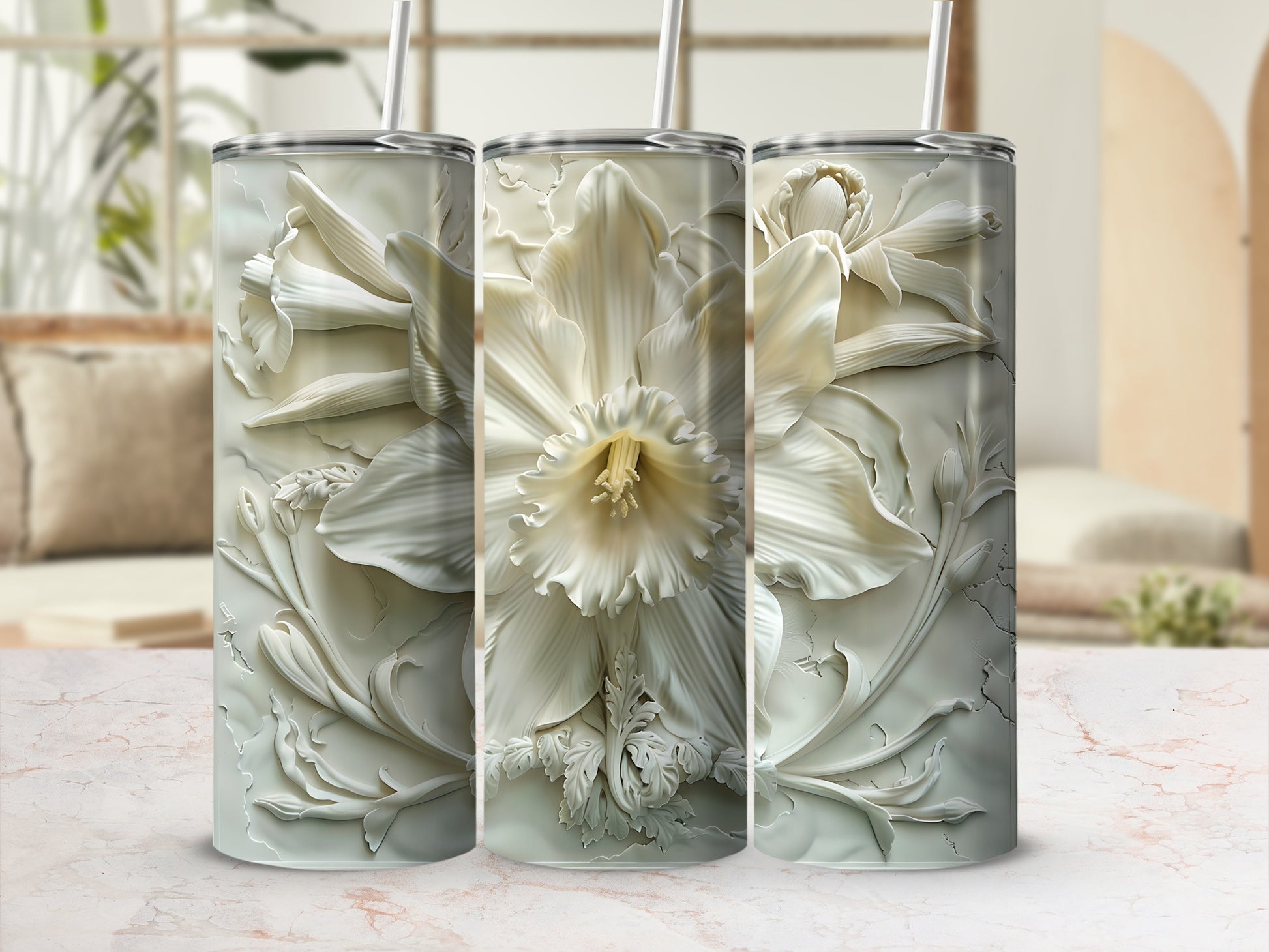 Three white floral relief tumblers with straws against a blurred background.