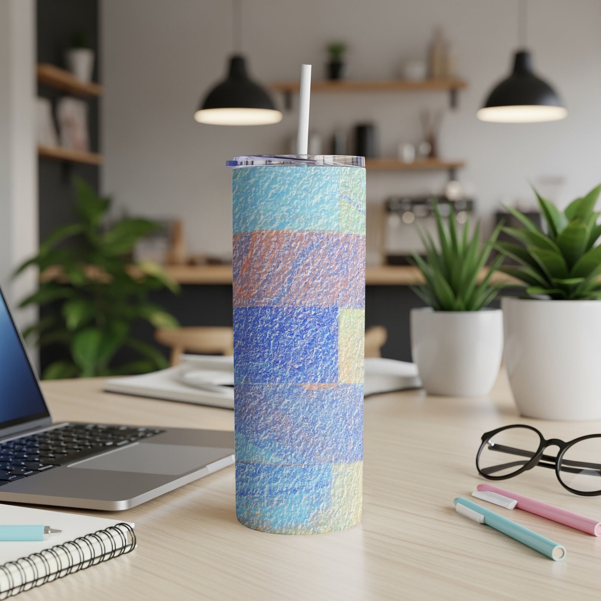 Textured blue and orange tumbler with a straw on a desk.