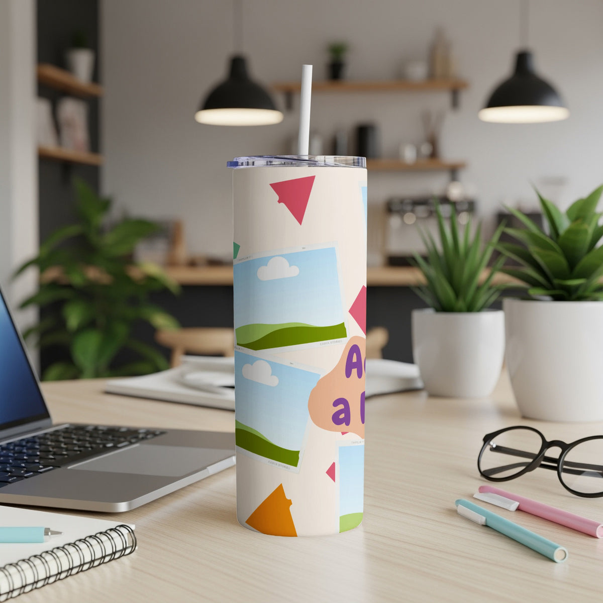 Tall tumbler with abstract shapes, photos, and text "A and a" on a desk.