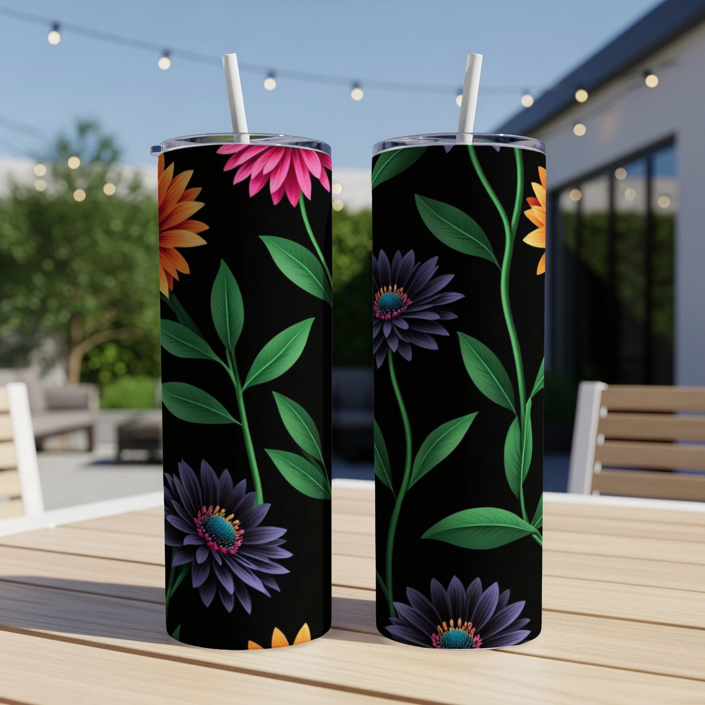 Two black tumblers with vibrant floral designs and straws on a table.