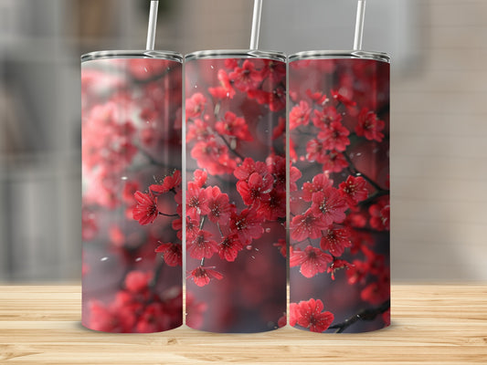 Three tumblers adorned with vibrant red cherry blossoms against a blurred background.