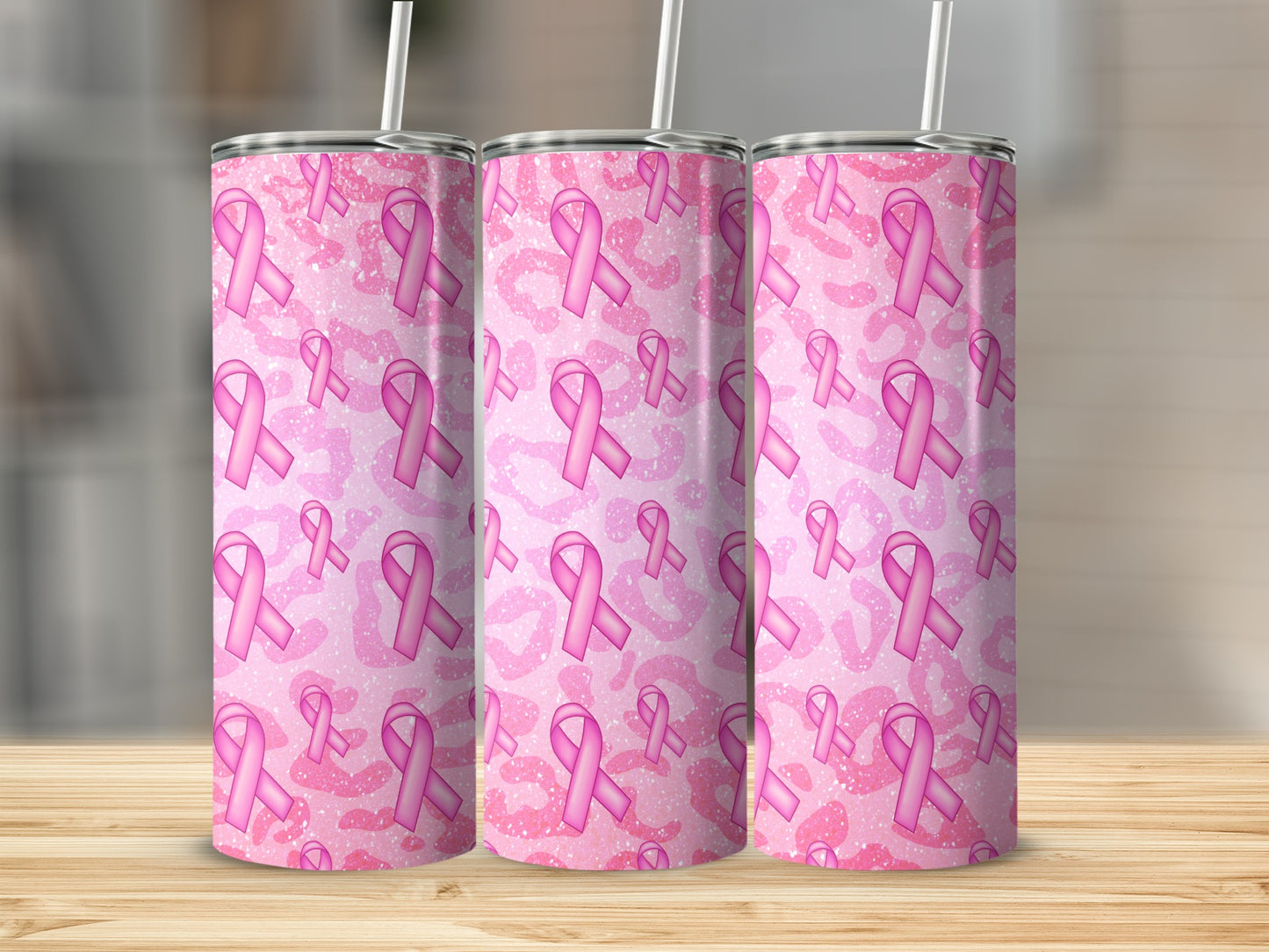 Three pink glittery breast cancer awareness ribbon tumblers on a wooden surface.