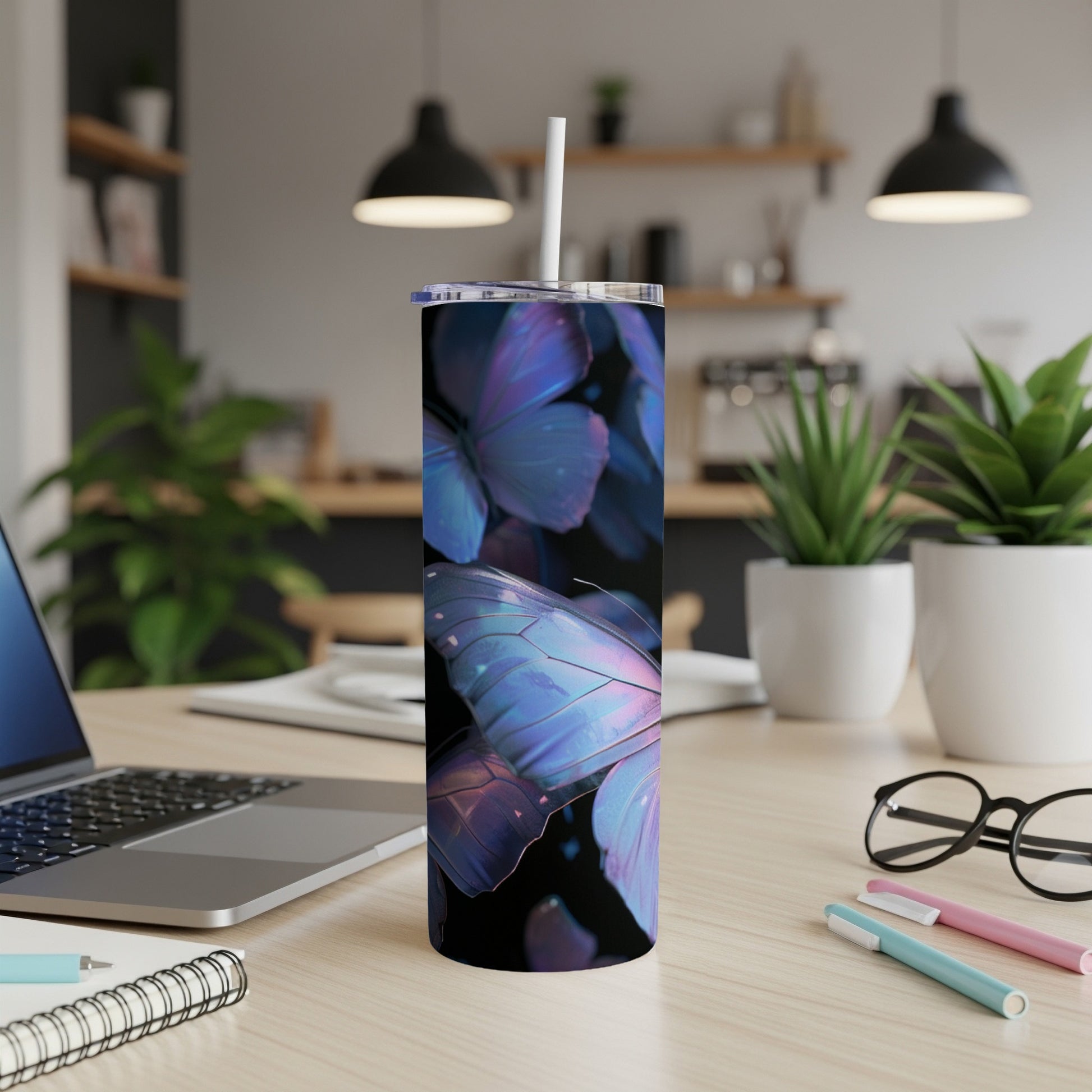 Tall tumbler with iridescent butterfly design and white straw on desk.