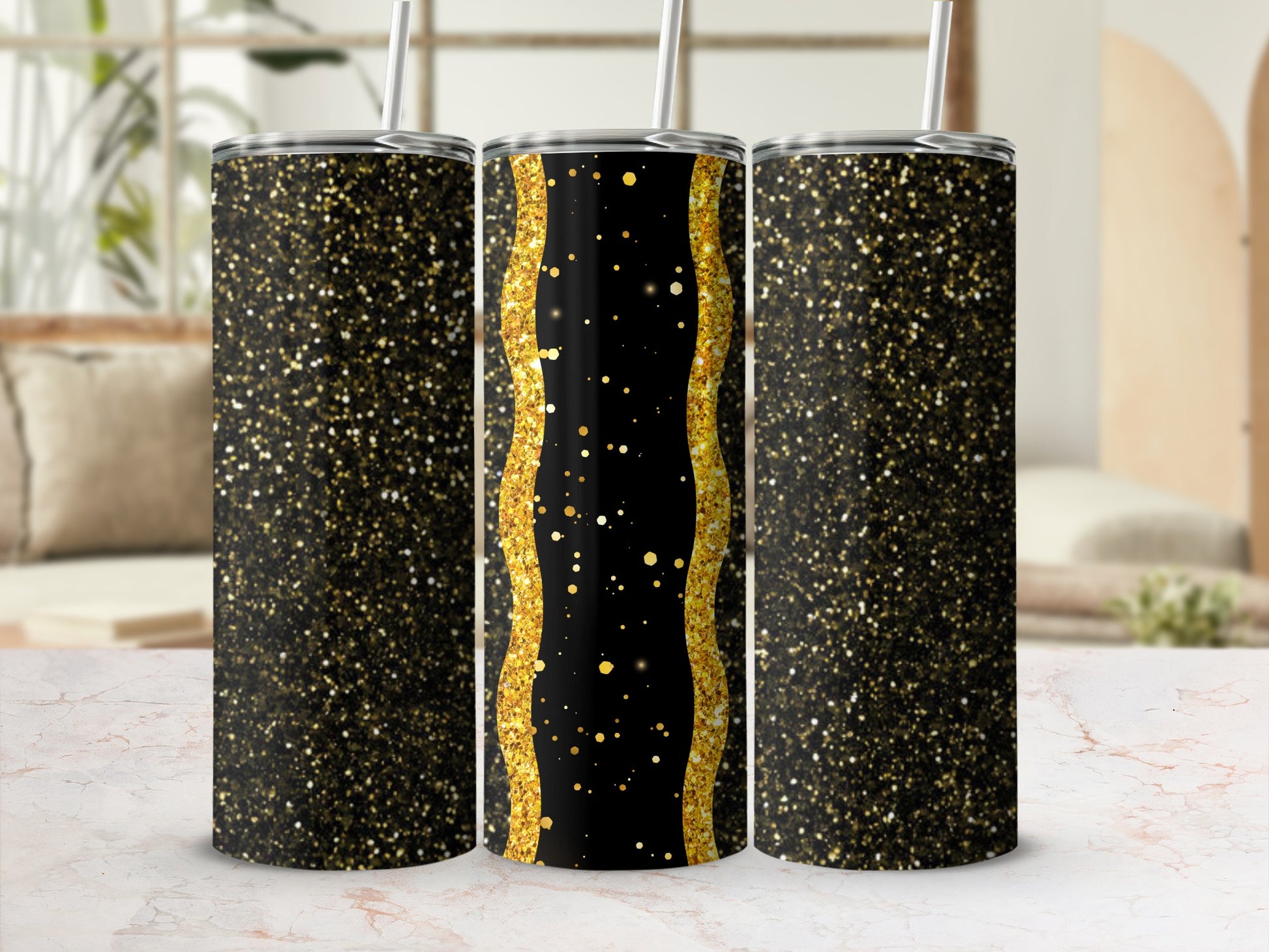 Three glittery black and gold tumblers with straws on a marble surface.