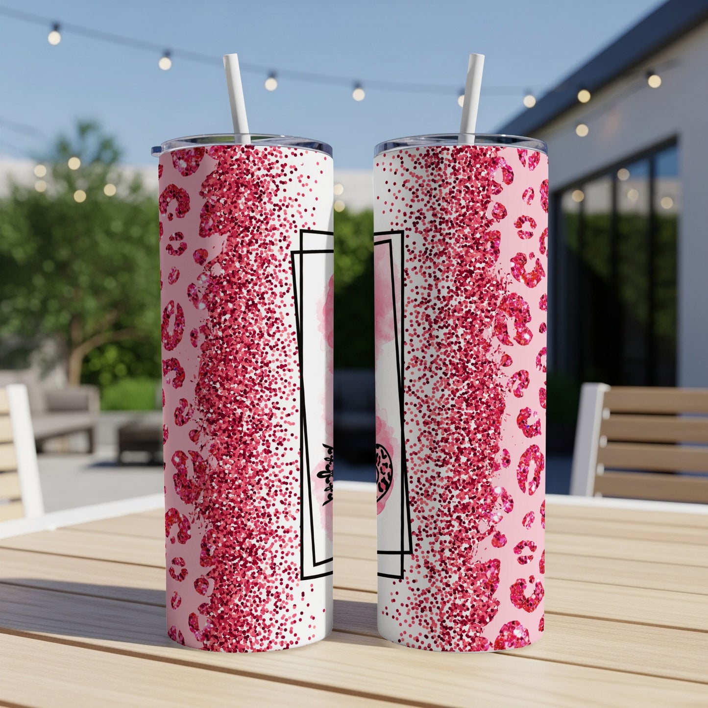 Two pink glitter leopard print tumblers with straws on a table.