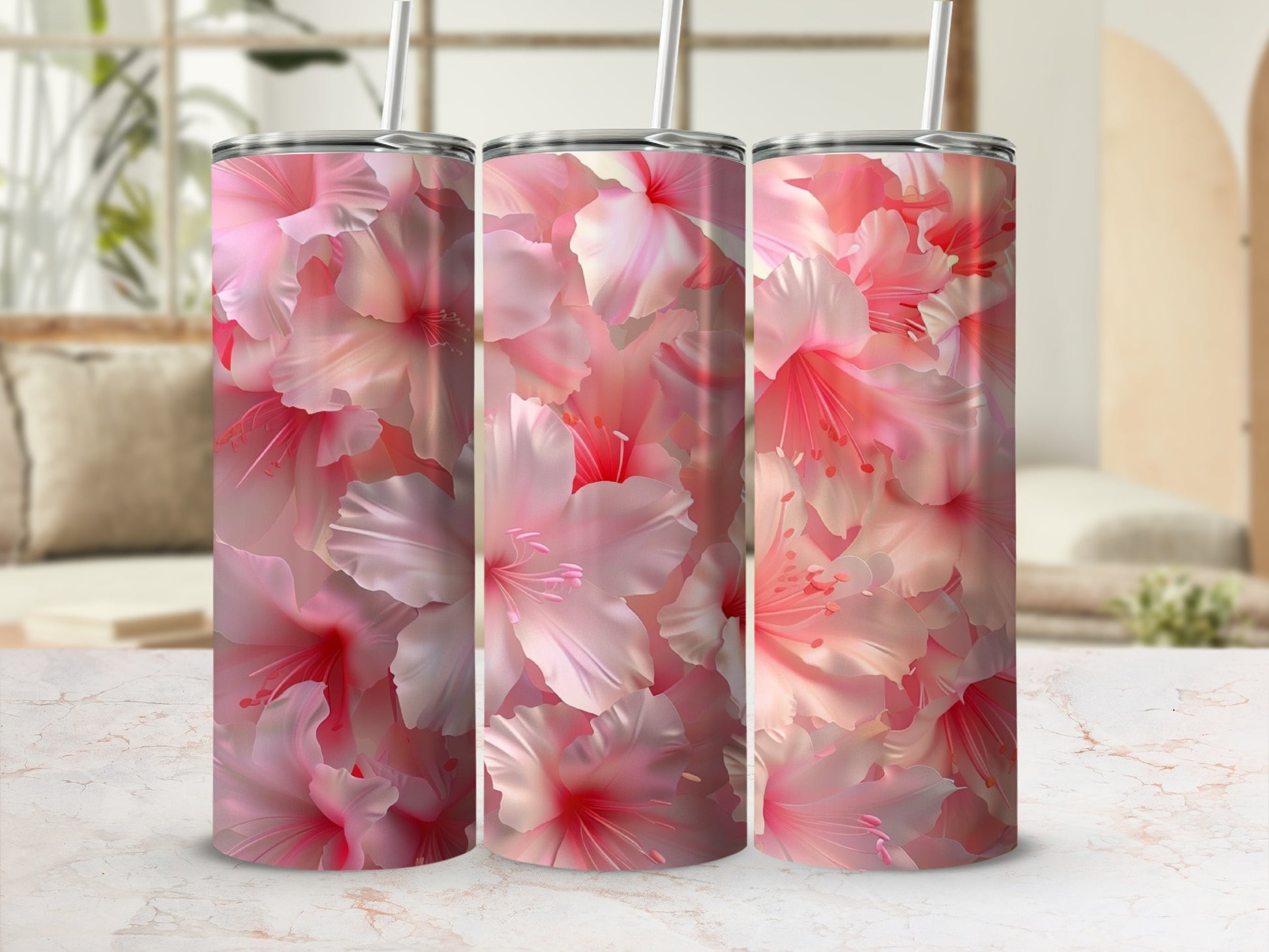 Three pink floral tumblers with straws on a marbled surface.