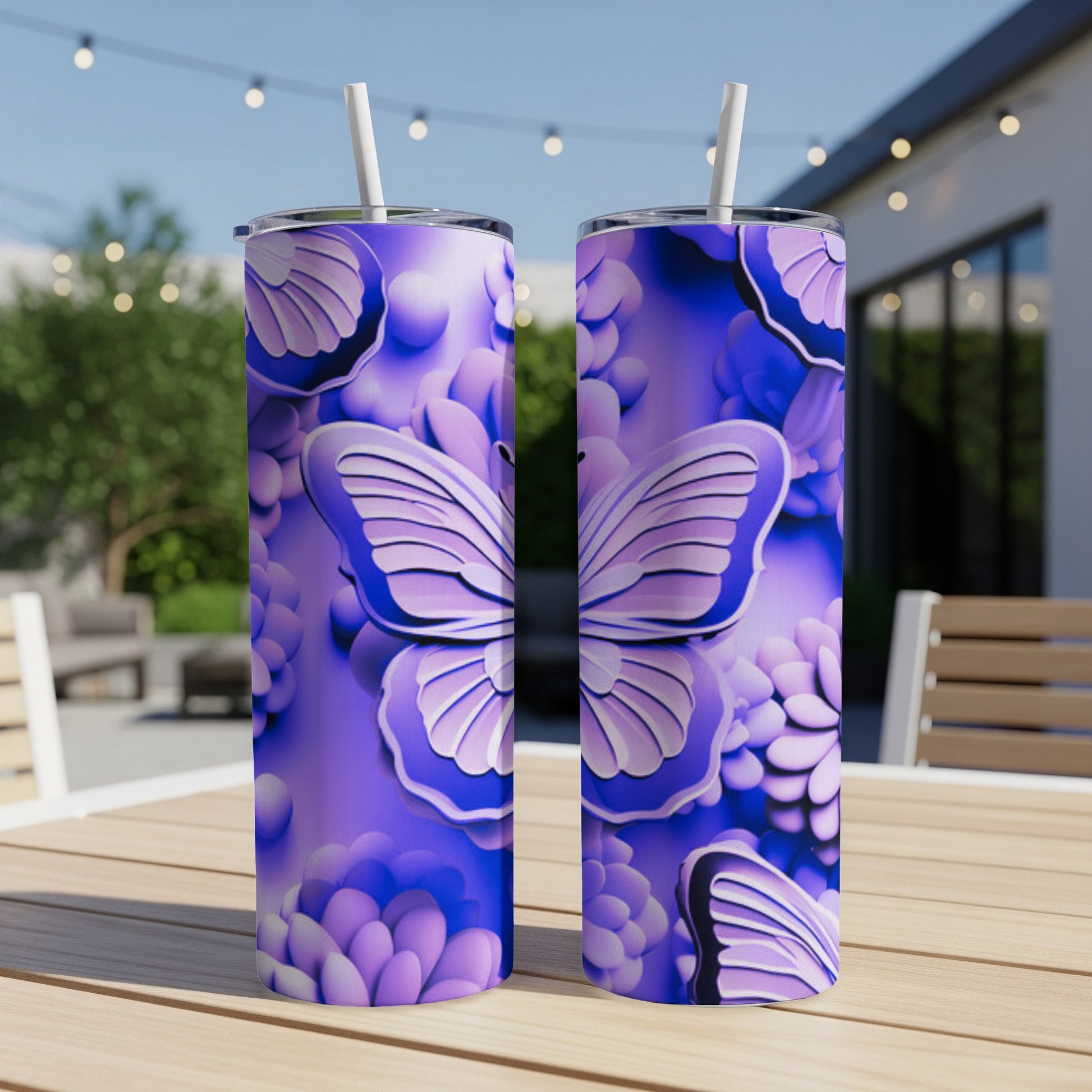 Two purple tumblers with butterfly and floral designs on a wooden table outdoors.