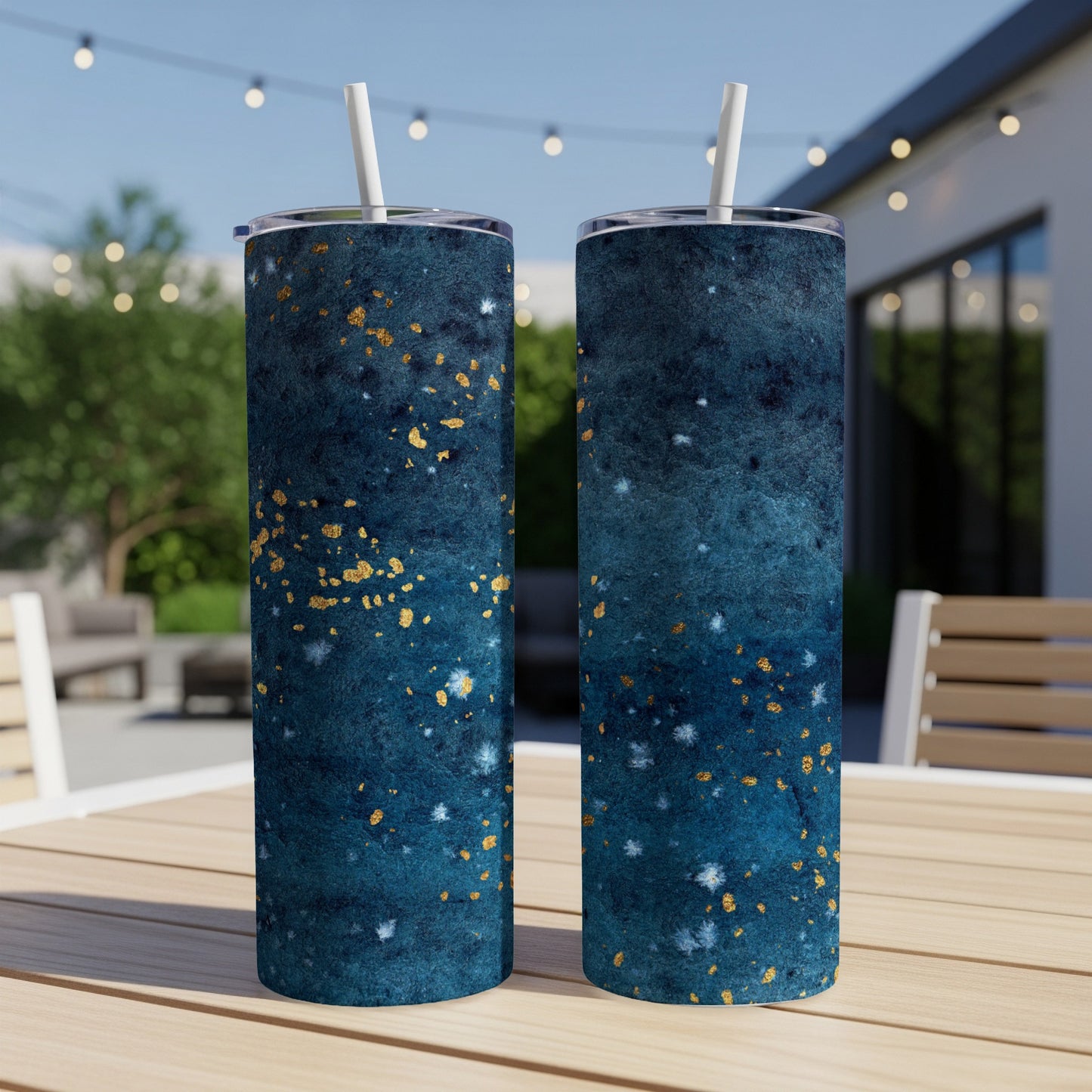 Two dark teal tumblers with gold speckles and white straws on a wooden table.
