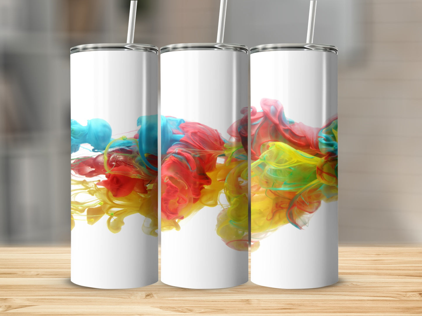 Three white tumblers with colorful paint swirls against a blurred background.