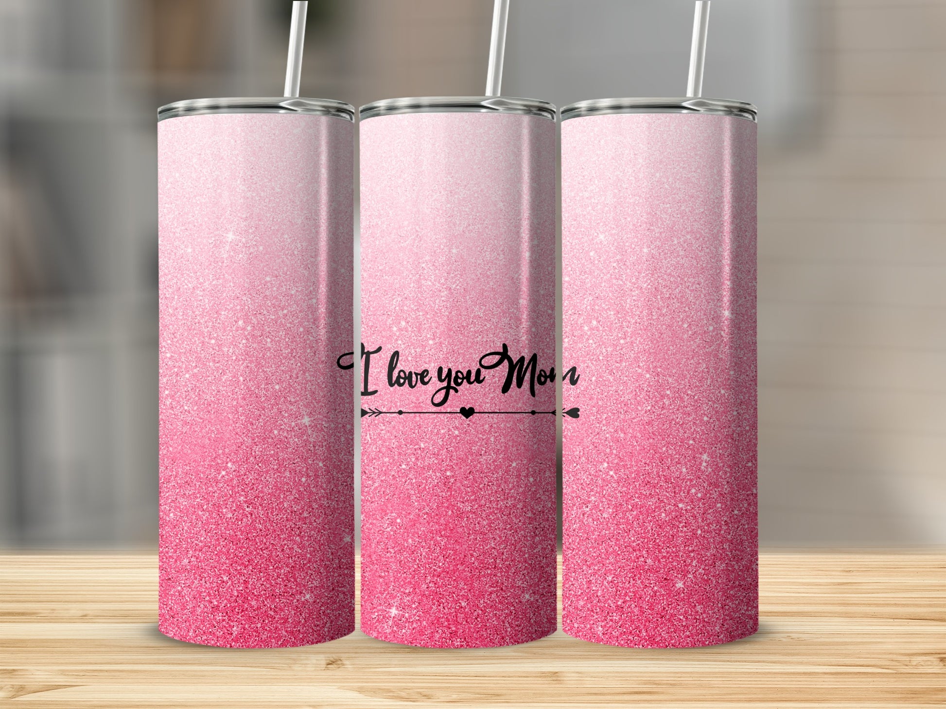 Pink glitter tumbler with "I Love You Mom" text on a wooden surface.