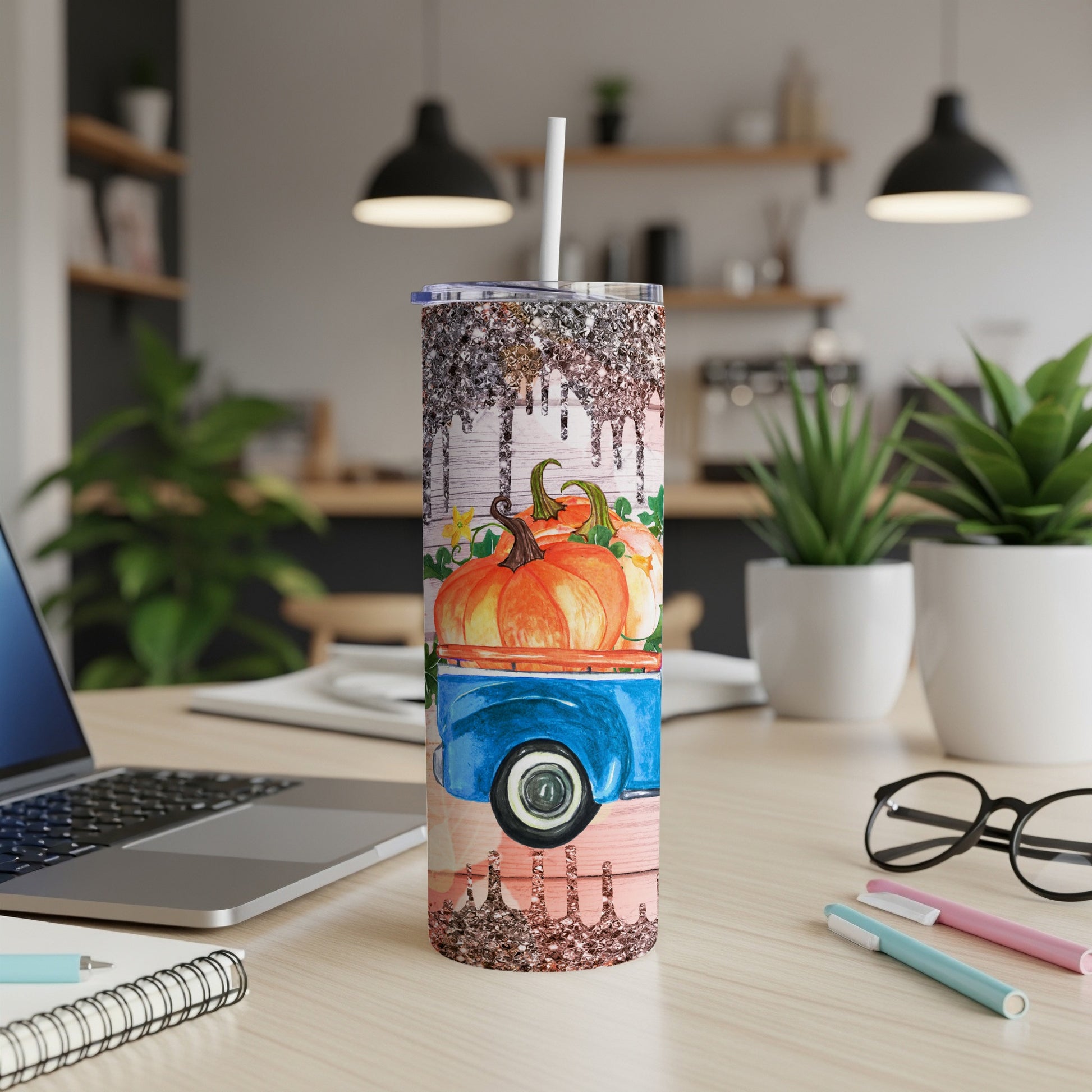 Tumbler with pumpkins on a blue truck, glitter accents, on a wooden desk.