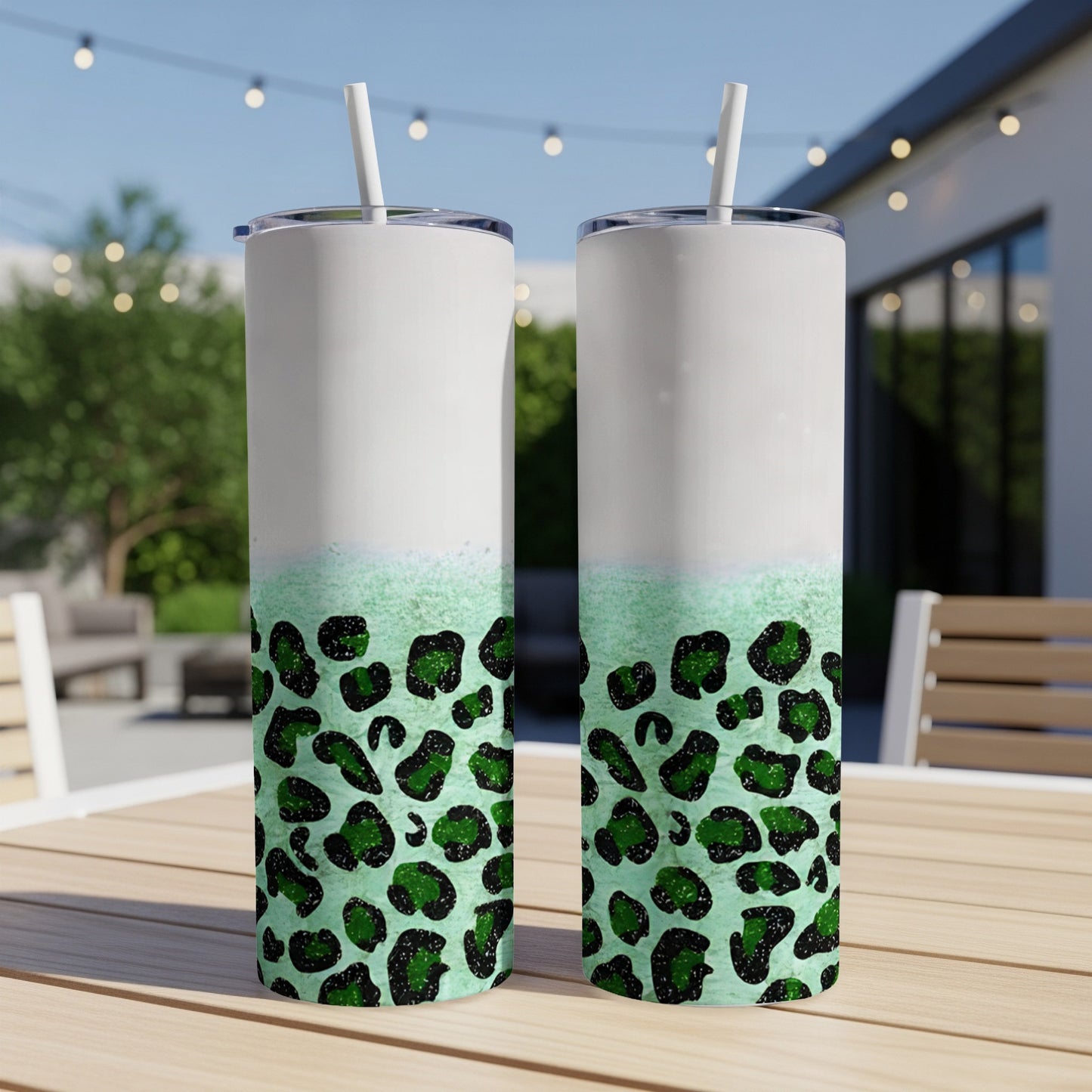 Two green leopard print tumblers with white tops and straws.