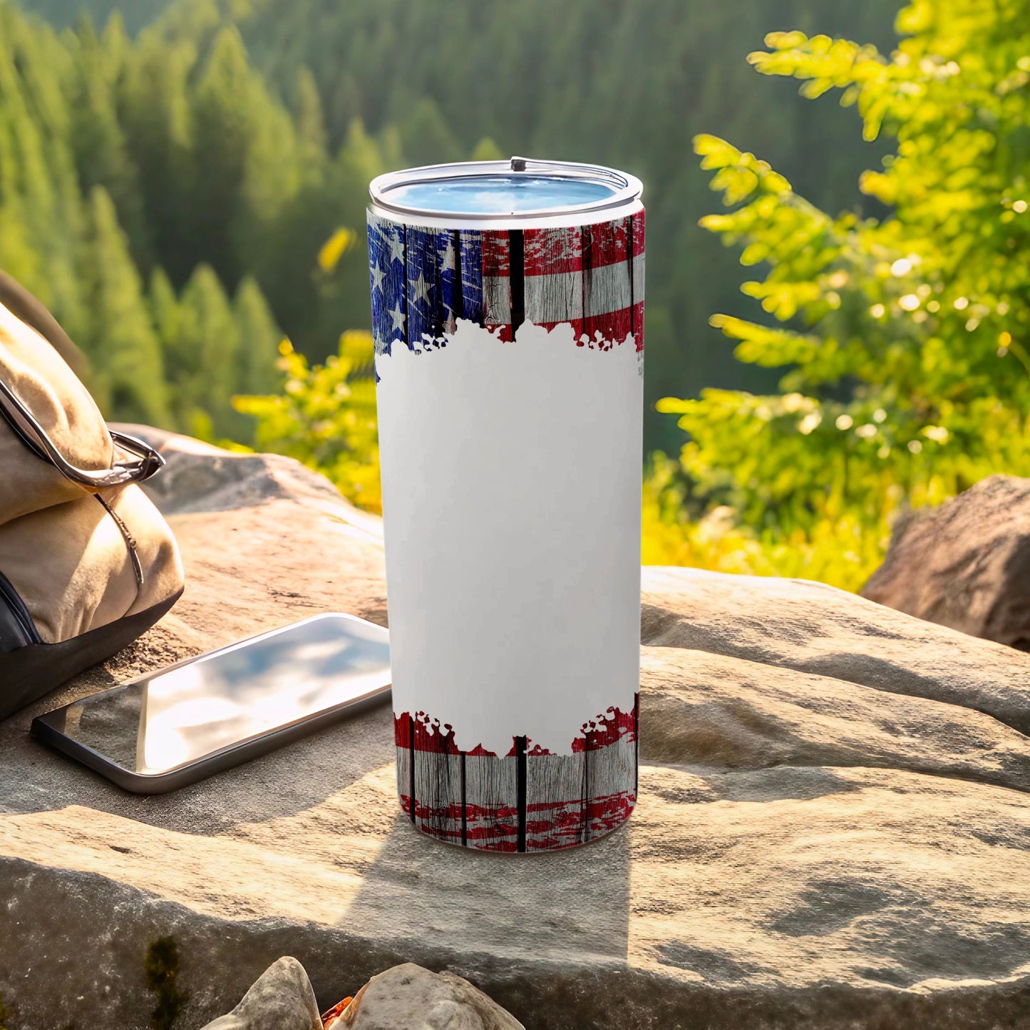American flag distressed wood tumbler on rock with backpack and phone.