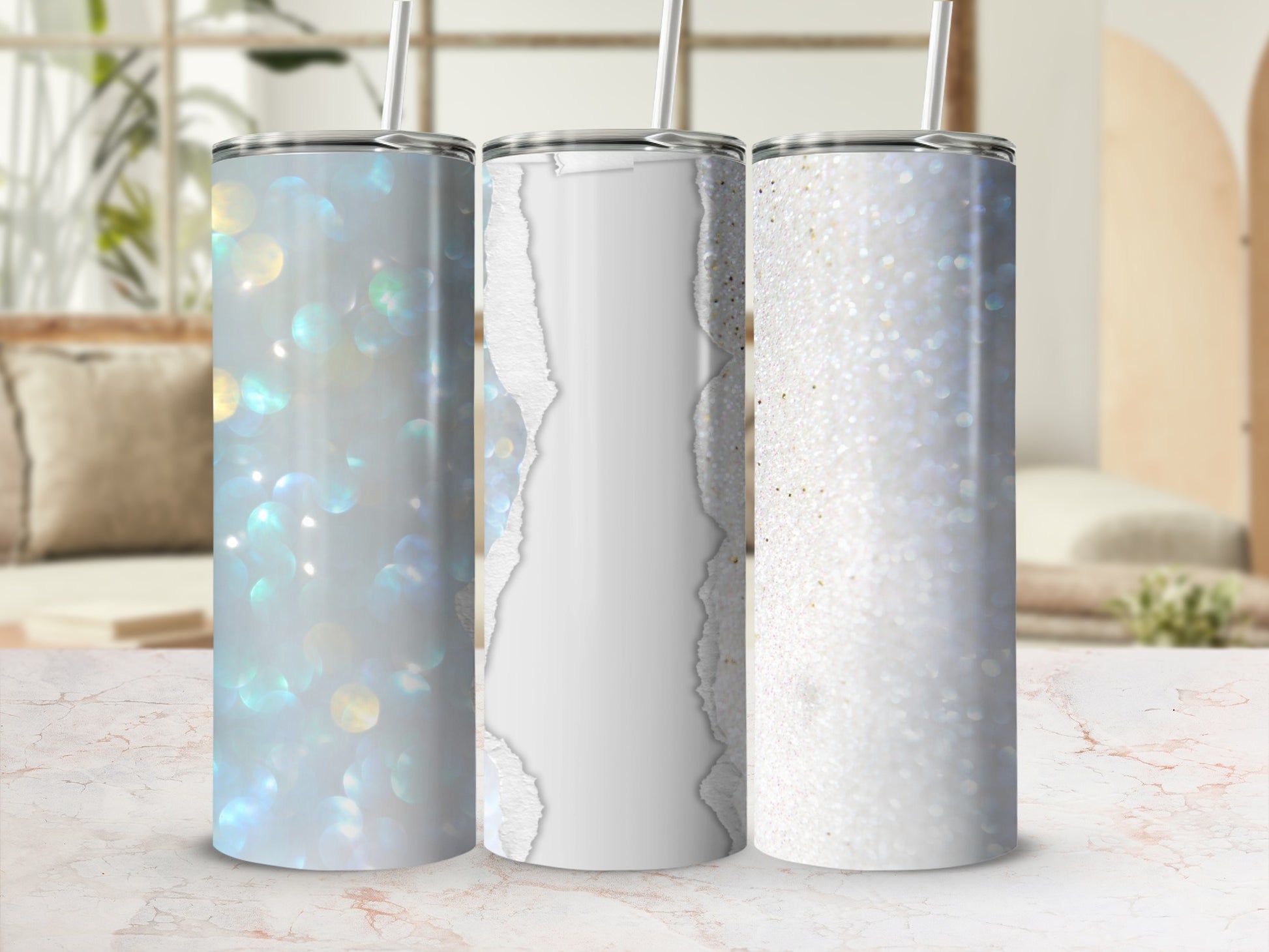 Three glitter tumblers with bokeh and torn paper designs on a marble surface.