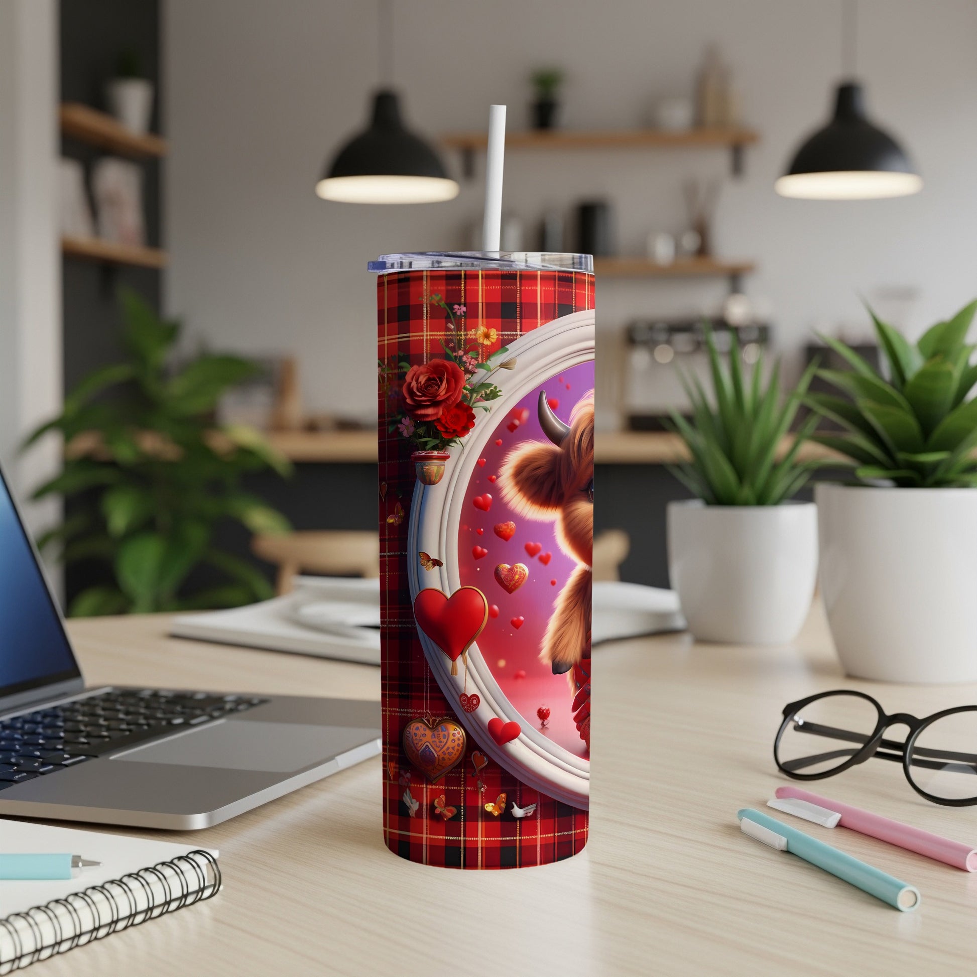 Red plaid tumbler with highland cow and hearts on a desk.