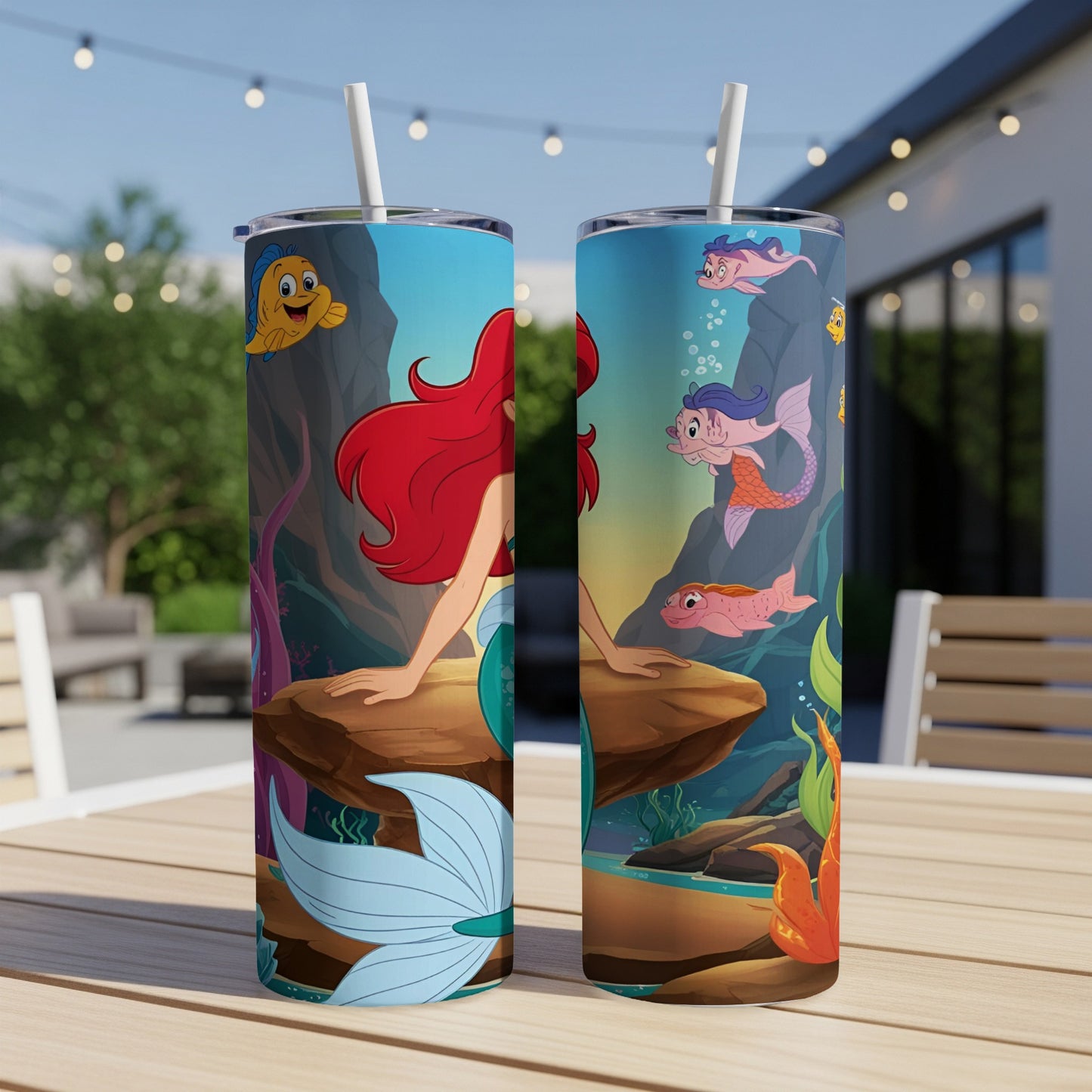 Ariel the mermaid and friends on a tumbler against a blurred outdoor background.