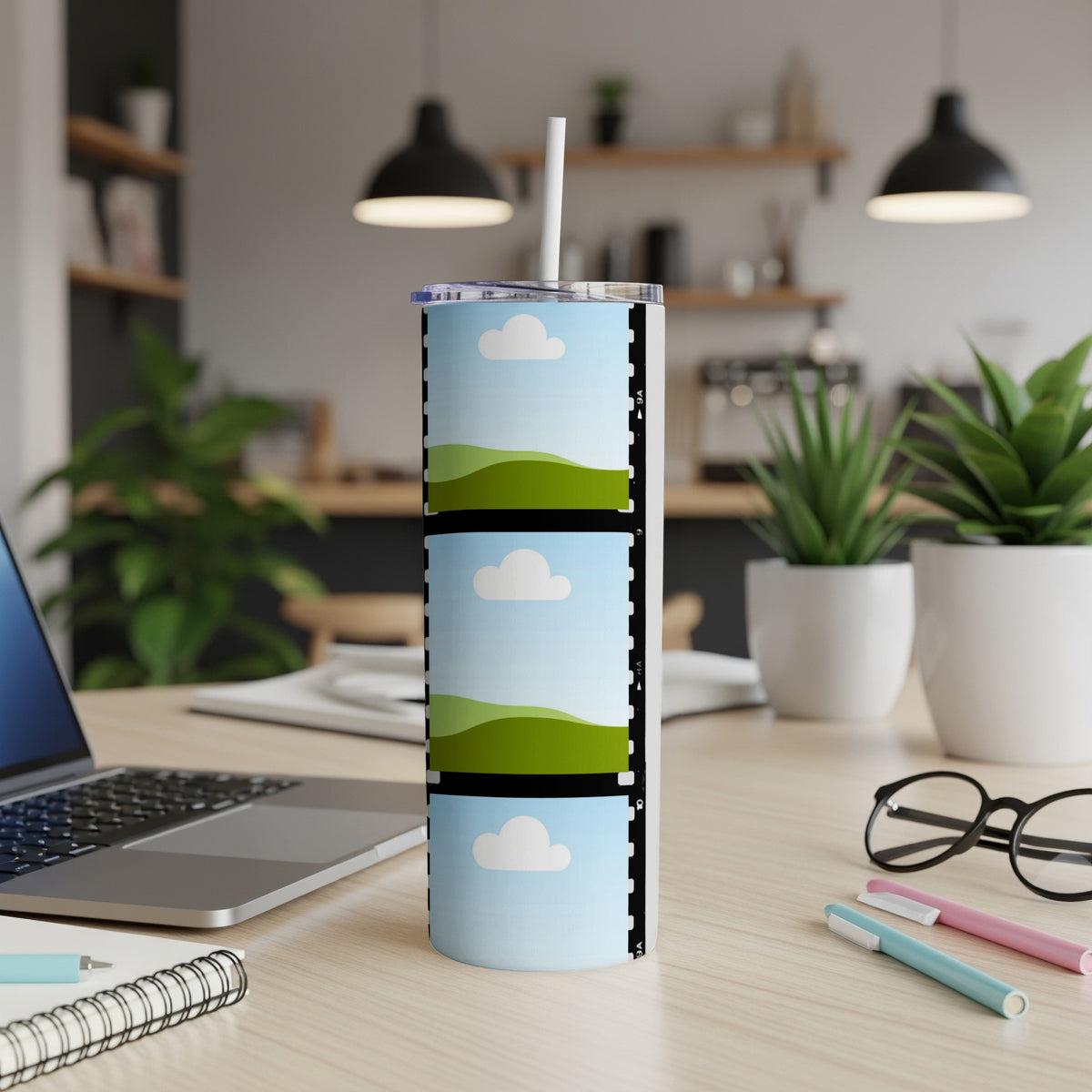 Tumbler with film strip design featuring three cartoon landscapes and sky scenes.