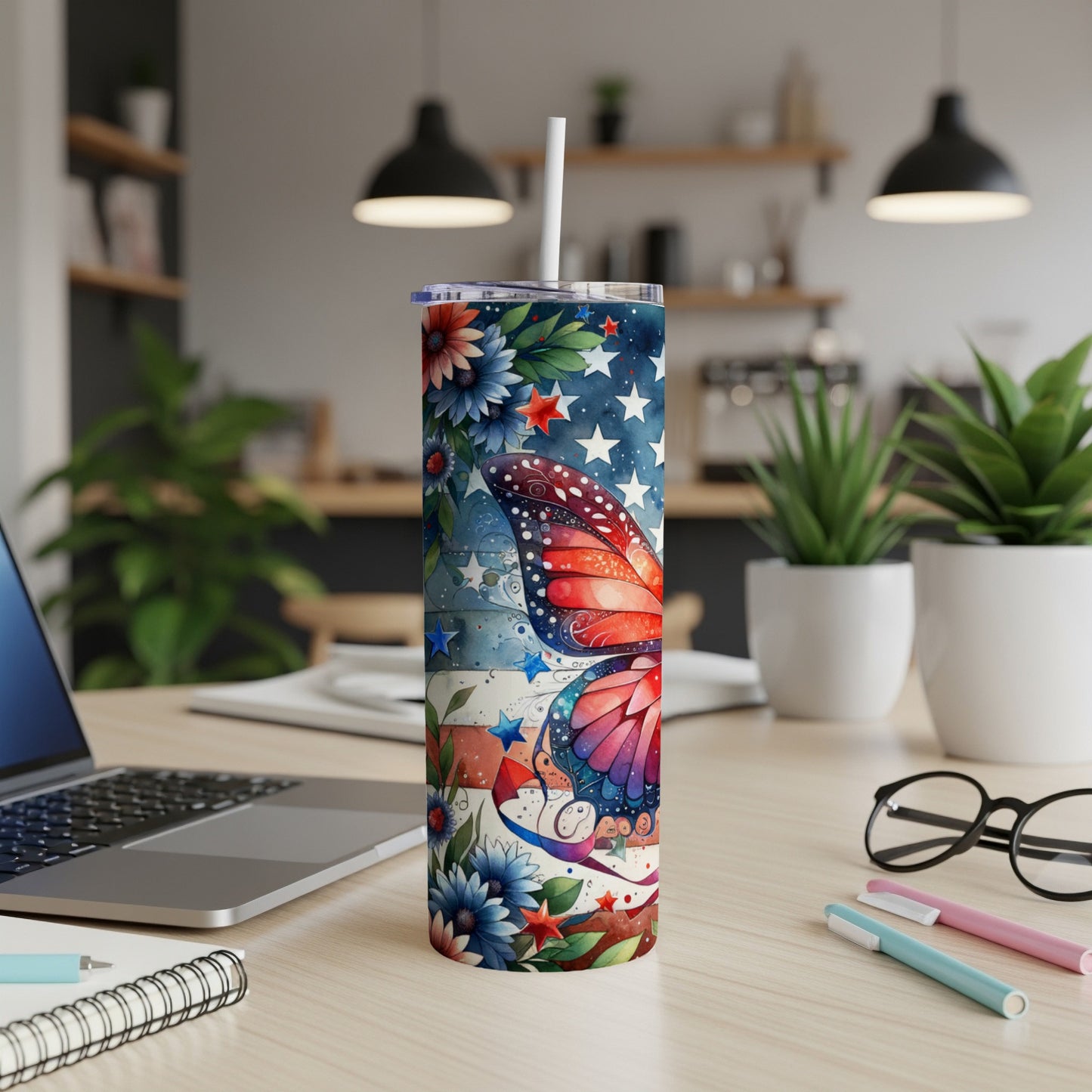 Tumbler with butterfly and American flag design, sitting on a desk.