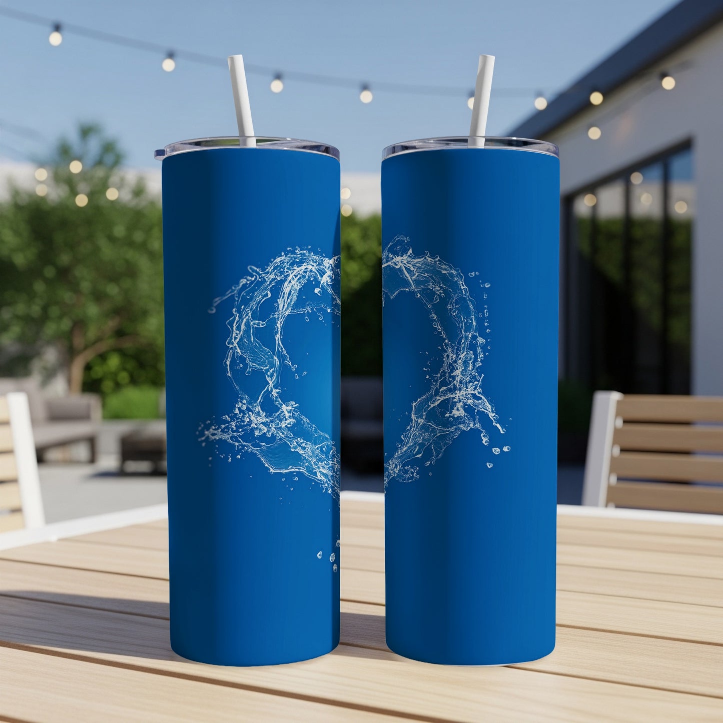 Two blue tumblers with white water splash design on an outdoor table.