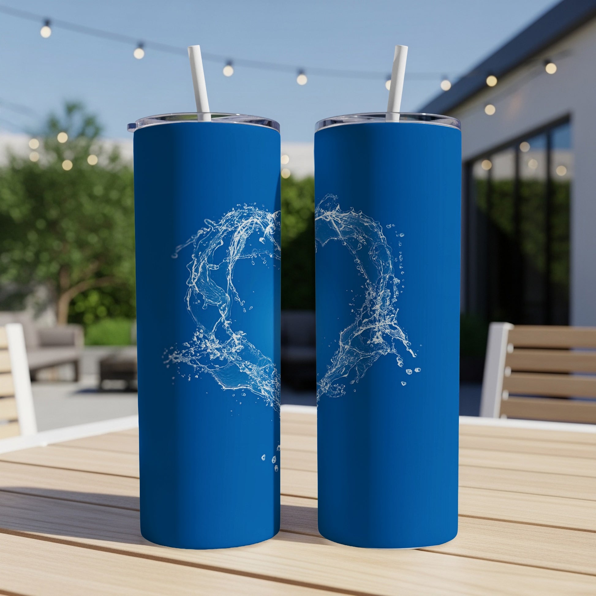 Two blue tumblers with white water splash design on an outdoor table.