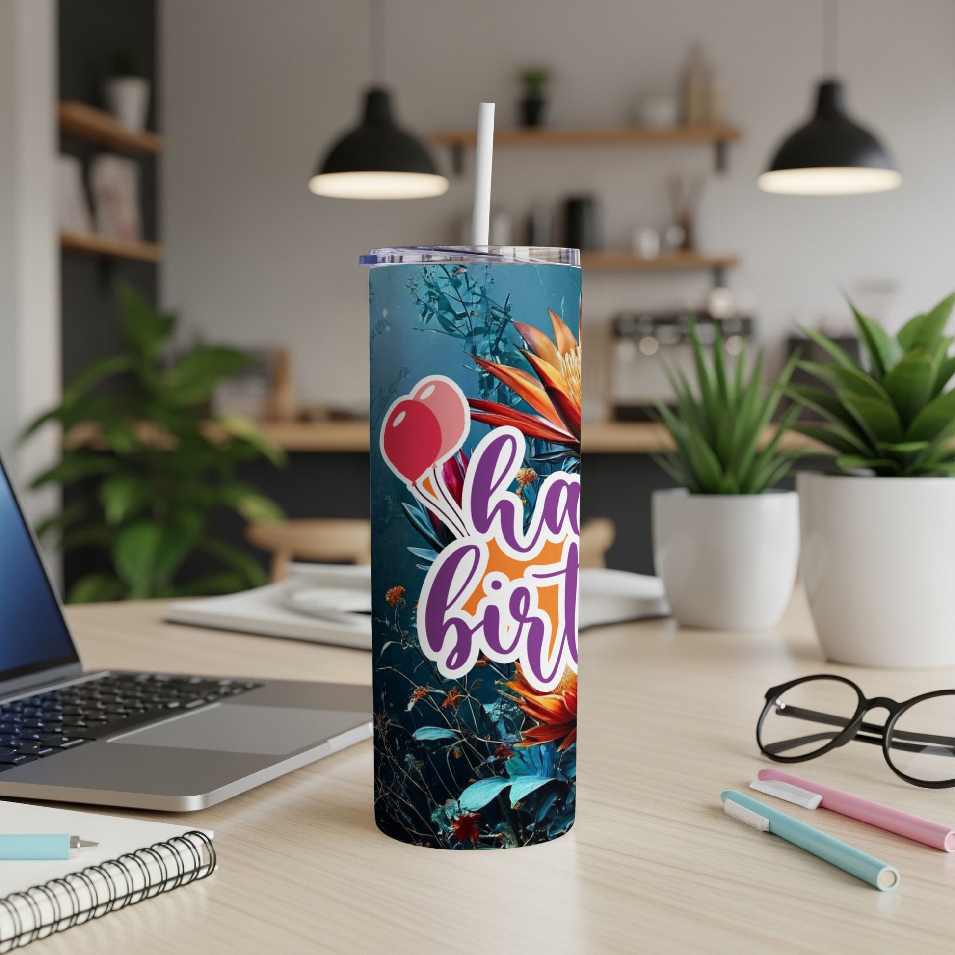 Floral tumbler with "Happy Birthday" text and balloons on a desk.