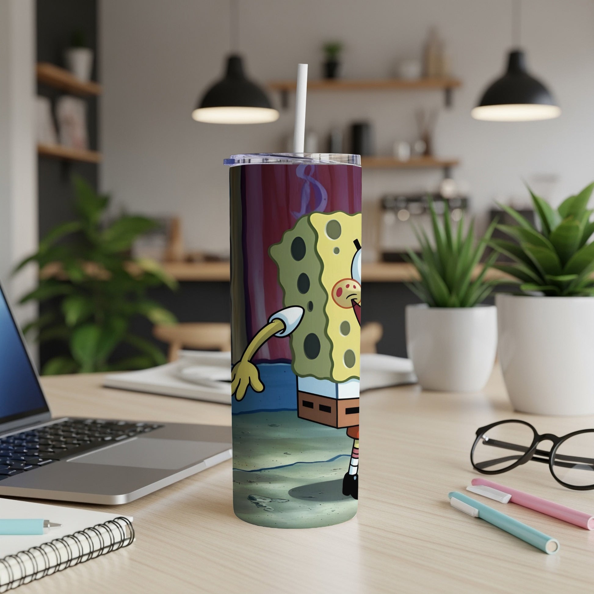 SpongeBob SquarePants tumbler with a straw, on a desk with a laptop and pens.