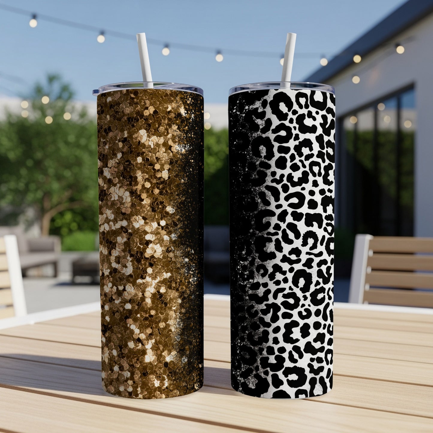 Two glitter and leopard print tumblers with straws on a wooden table.