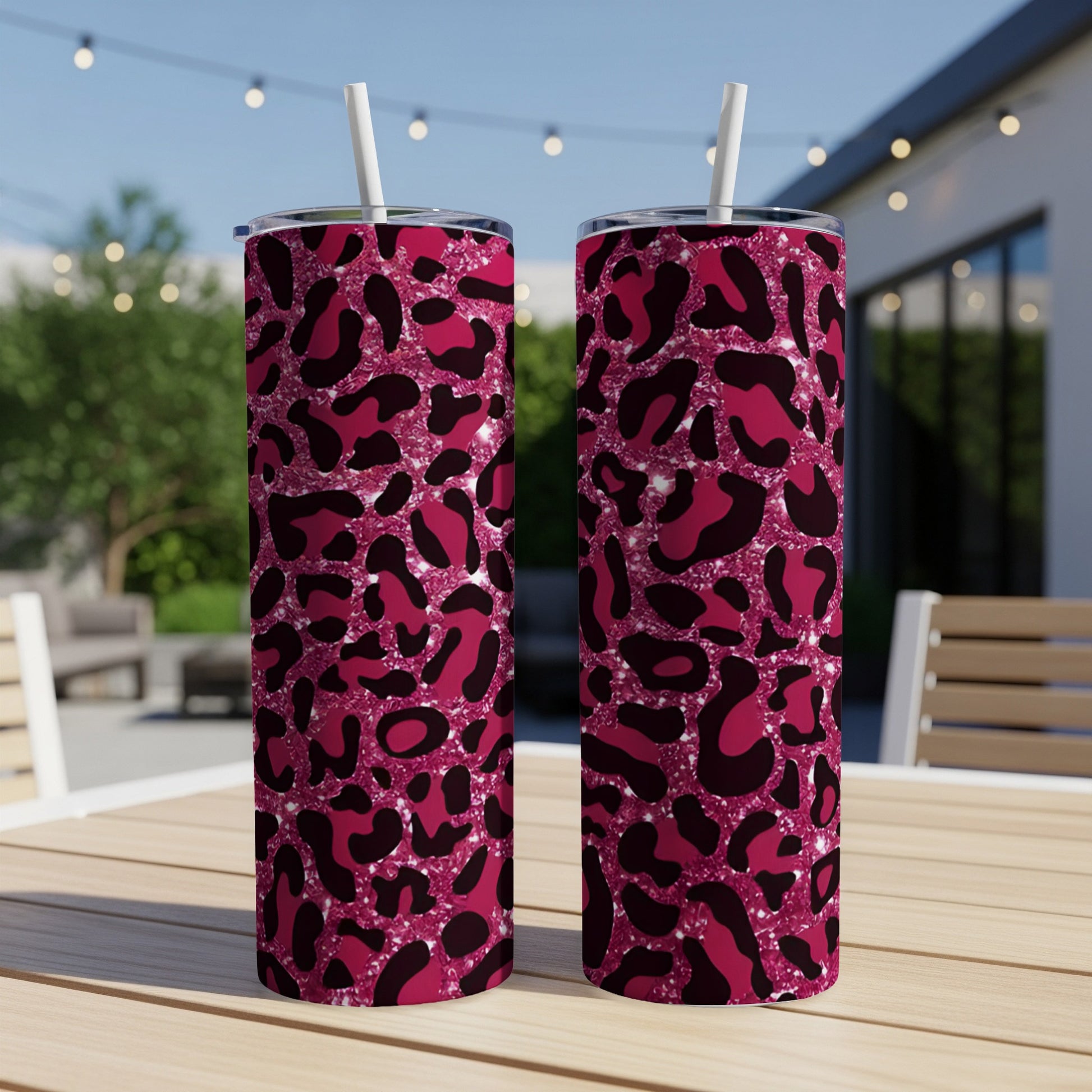 Two tall tumblers with a pink leopard print pattern on a wooden table.