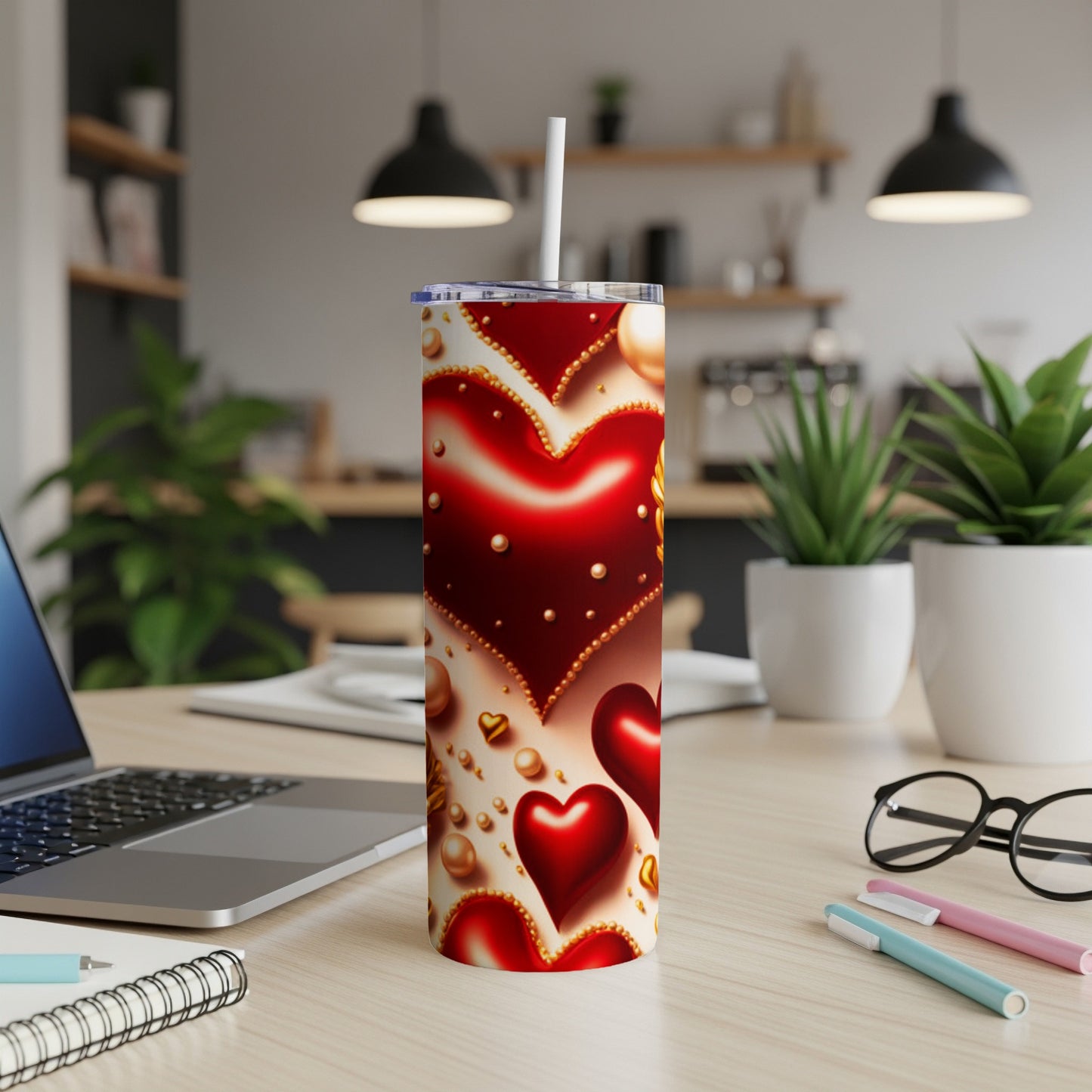 Red tumbler with heart designs and golden beads, topped with a straw.