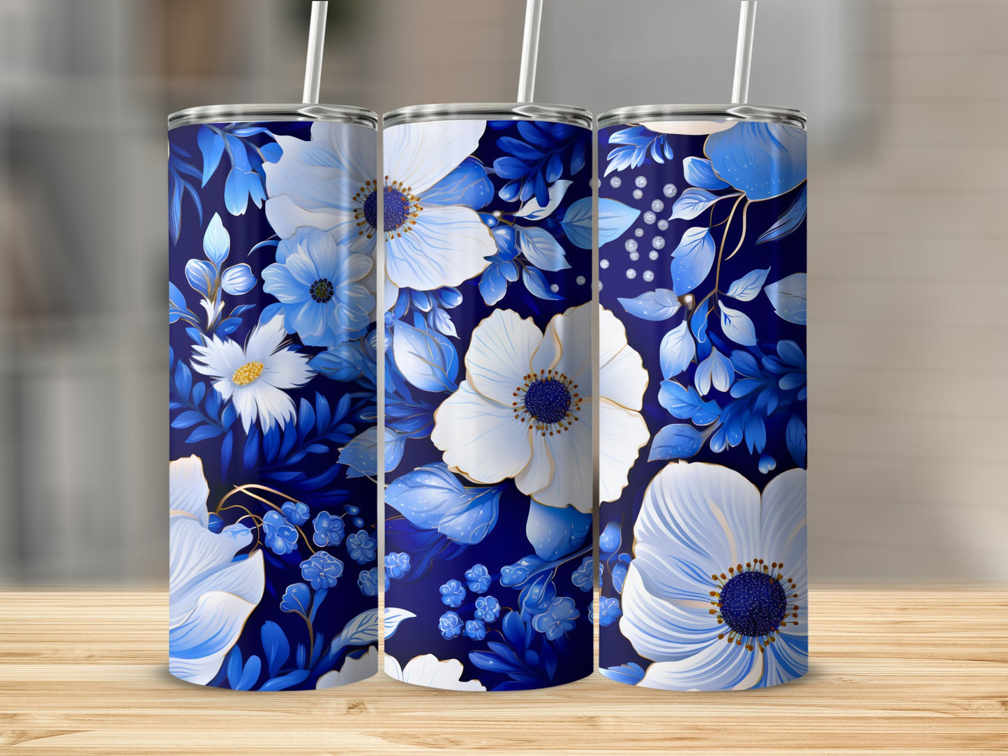 Three blue floral tumblers with white and gold flowers on a wooden surface.
